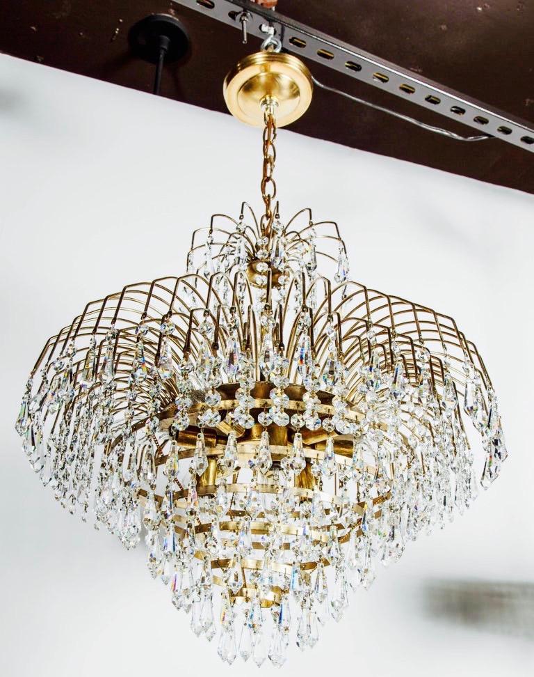 Mid-Century Modern chandelier with waterfall frame and cut crystals evoking Victorian Era chandeliers. Brass frame features multiple cascading tiers, fitted with hundreds of suspended cut crystal pendants and crystal beads. The frame is comprised of