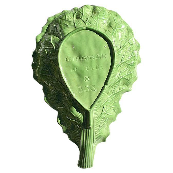 A beautiful green ceramic lettuce ware platter in the style of Dodie Thayer. This serving platter will be fabulous at your next dinner party or for a family supper. The trompe l'oeil leaf is elongated, with a long stem that serves as a handle for