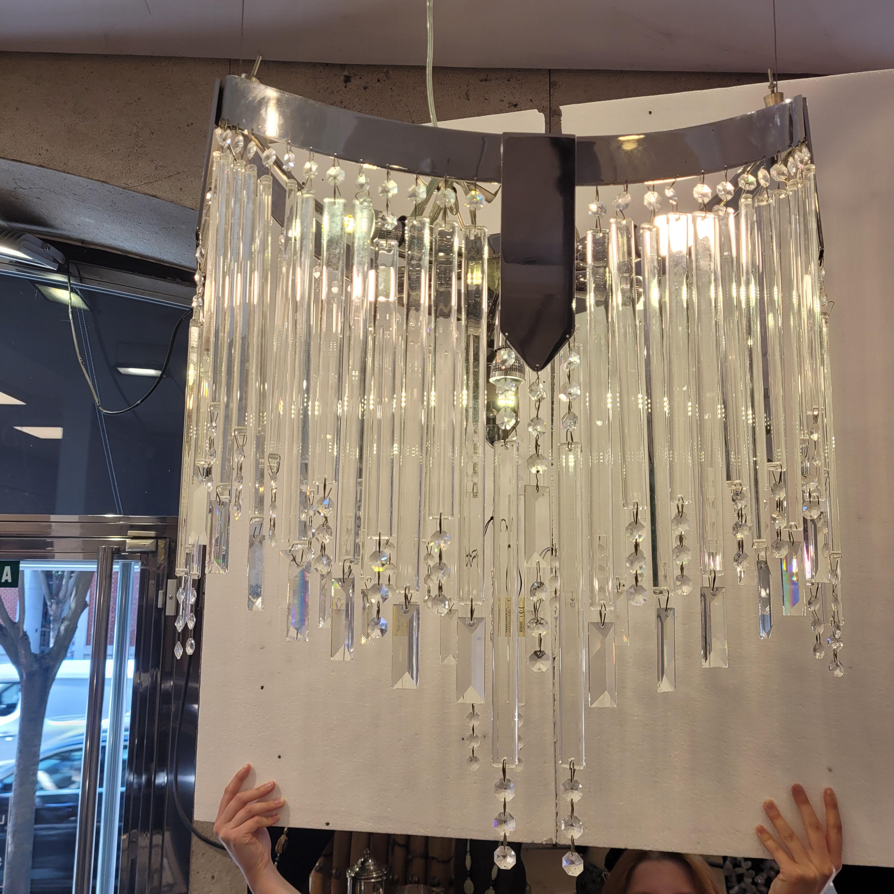 Eccezionale  lampadario o lampada da soffitto con cristalli a taglio geometrico e una struttura metallica ovale e concava.

Presenta una struttura in alluminio curvo, ovale e concavo da cui pendono circa 60 catene di cristallo allungate e tagliate