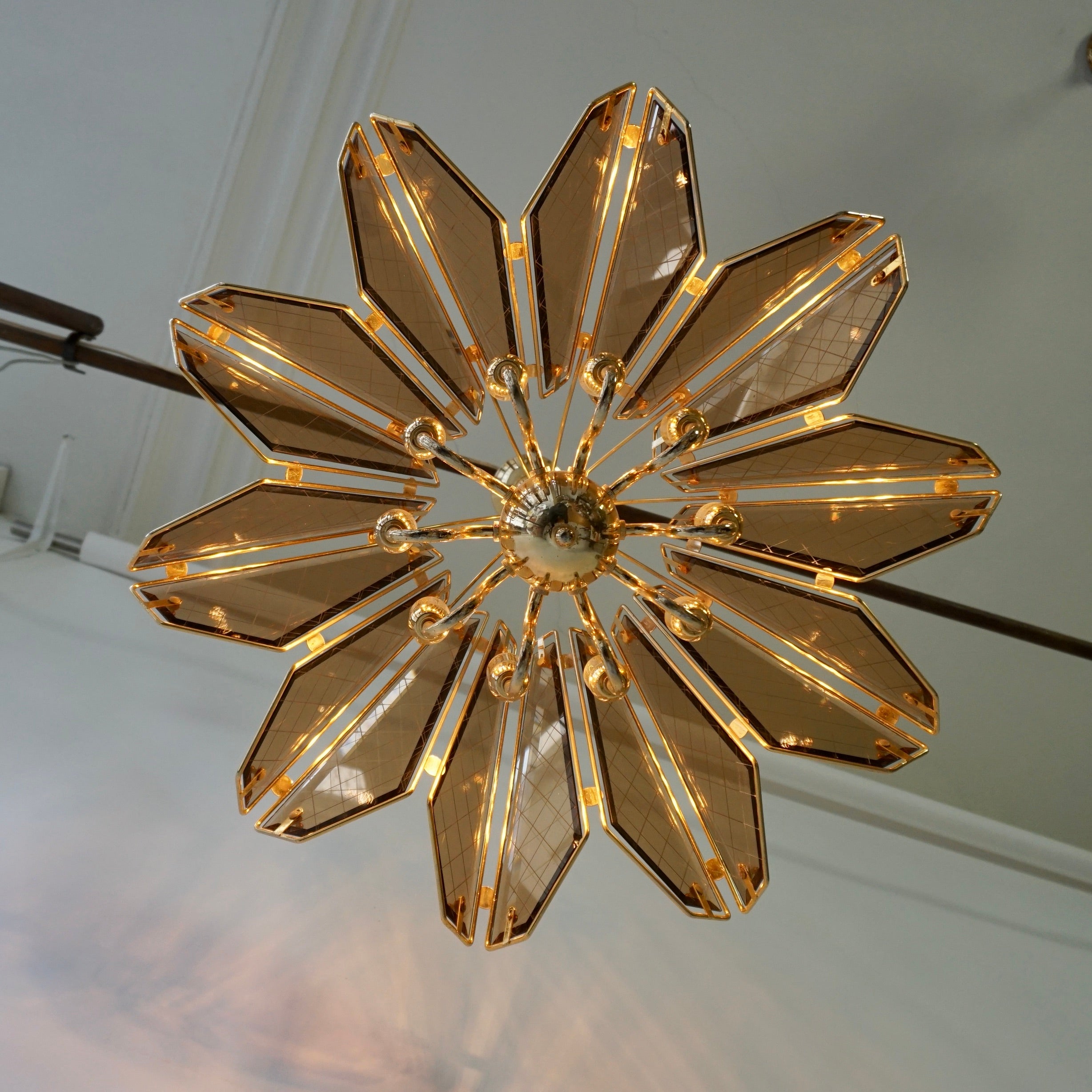 A large Italian Hollywood Regency ten-armed chandelier manufactured in the mid-century (1960s and 1970s). 

Chandelier in the Hollywood Regency style. Made of smoked glass and brass. The panels are facet cut. One of the panels has a mini chip on the
