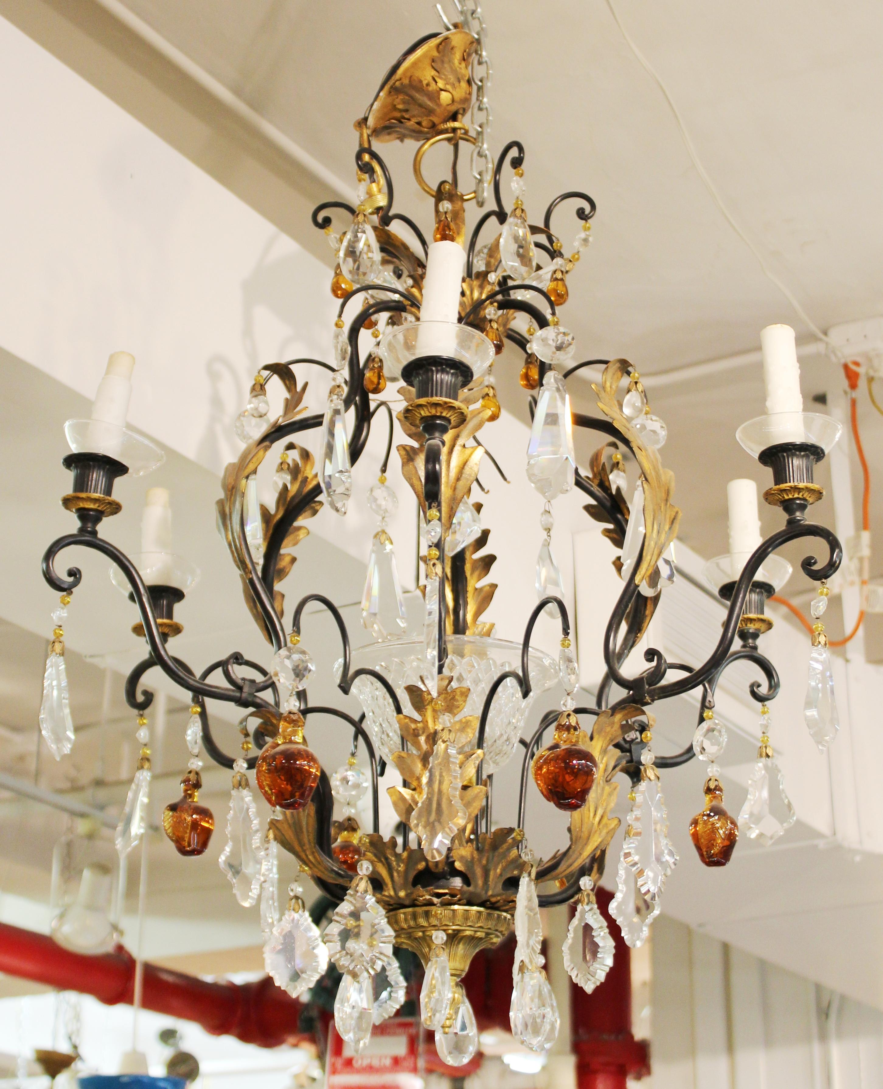 Hollywood Regency chandelier in wrought metal with gilt acanthus foliage elements and crystal and glass fruit drops. In great vintage condition with age-appropriate wear and use. 

Dealer: S138XX