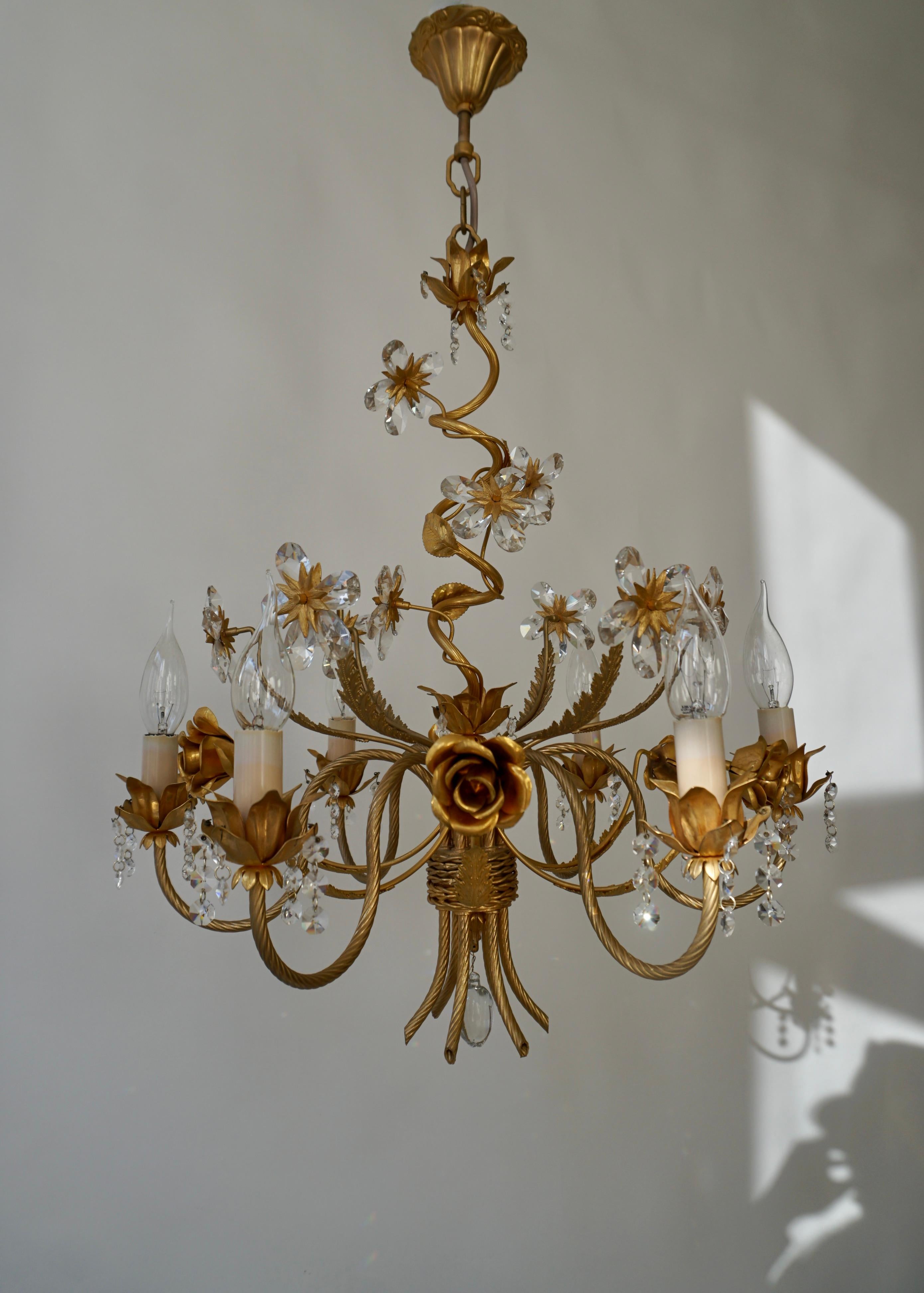 A beautiful elegant chandelier with Crystal flowers and gilded roses.

A Hollywood Regency six-armed chandelier from Italy manufactured in the mid-century (1960s and 1970s). The chandelier has six sockets for small incandescent lamps with screw base
