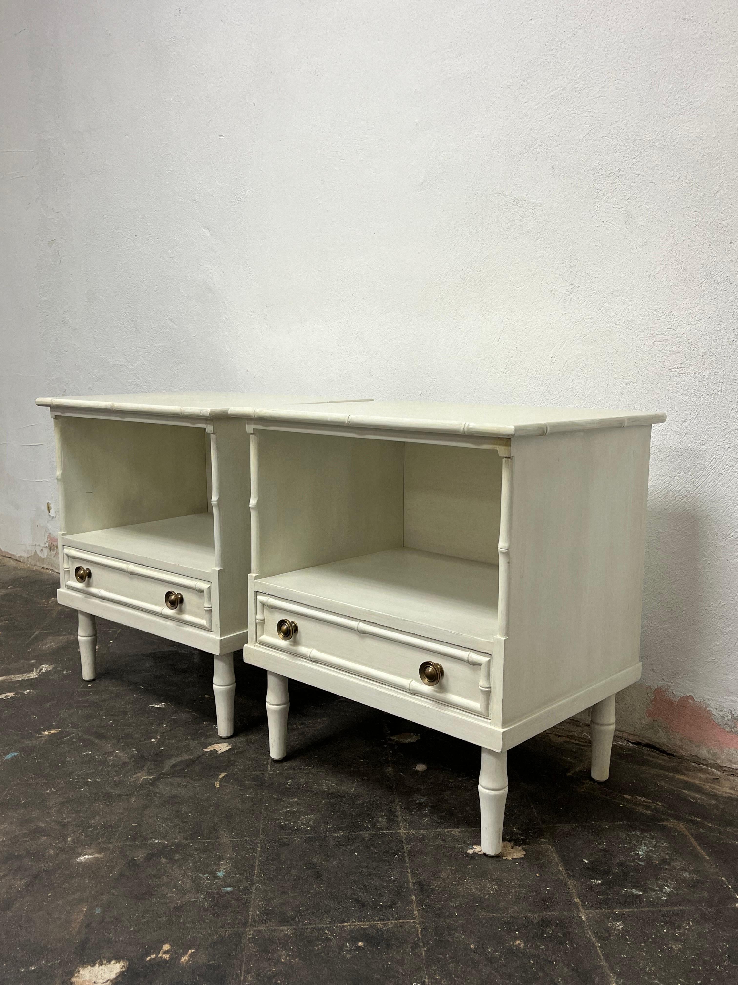 Classic mid century faux bamboo nightstands in a dry brush finish. Heavy construction with deep faux bamboo detail. Single bottom drawers with heavy brass bullseye drawer pulls. Nice tall open upper storage area. in the manner of Thomasville and