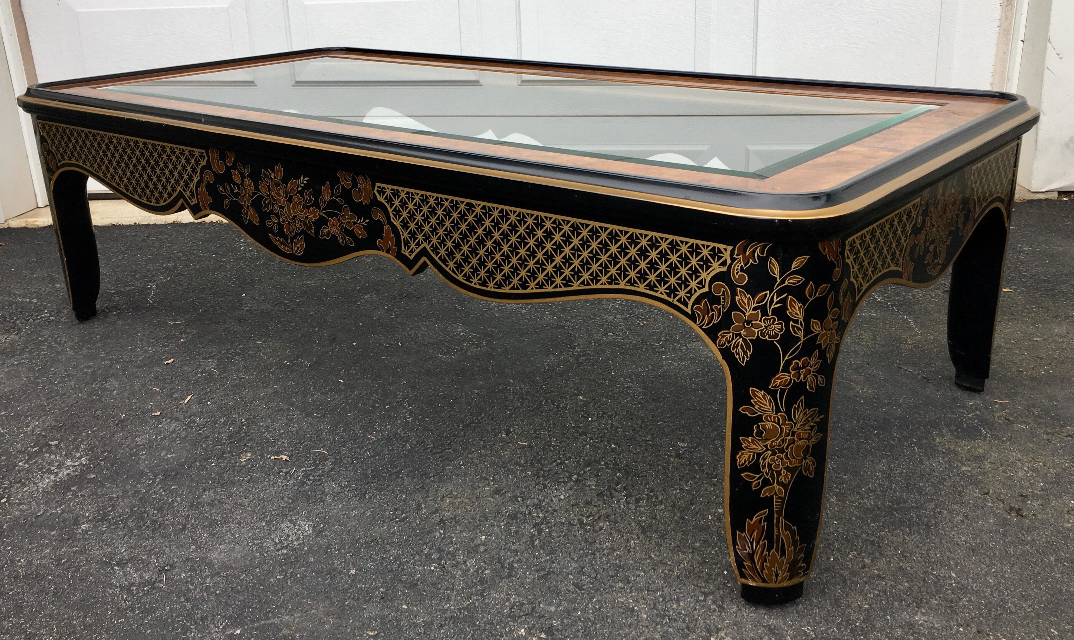 Rectangular Hollywood Regency burl wood and glass coffee table by Drexel Furniture. This sculptural cocktail table features original gloss black wood frame with hand painted gold leaf detailing of fretwork and floral design. Includes original and