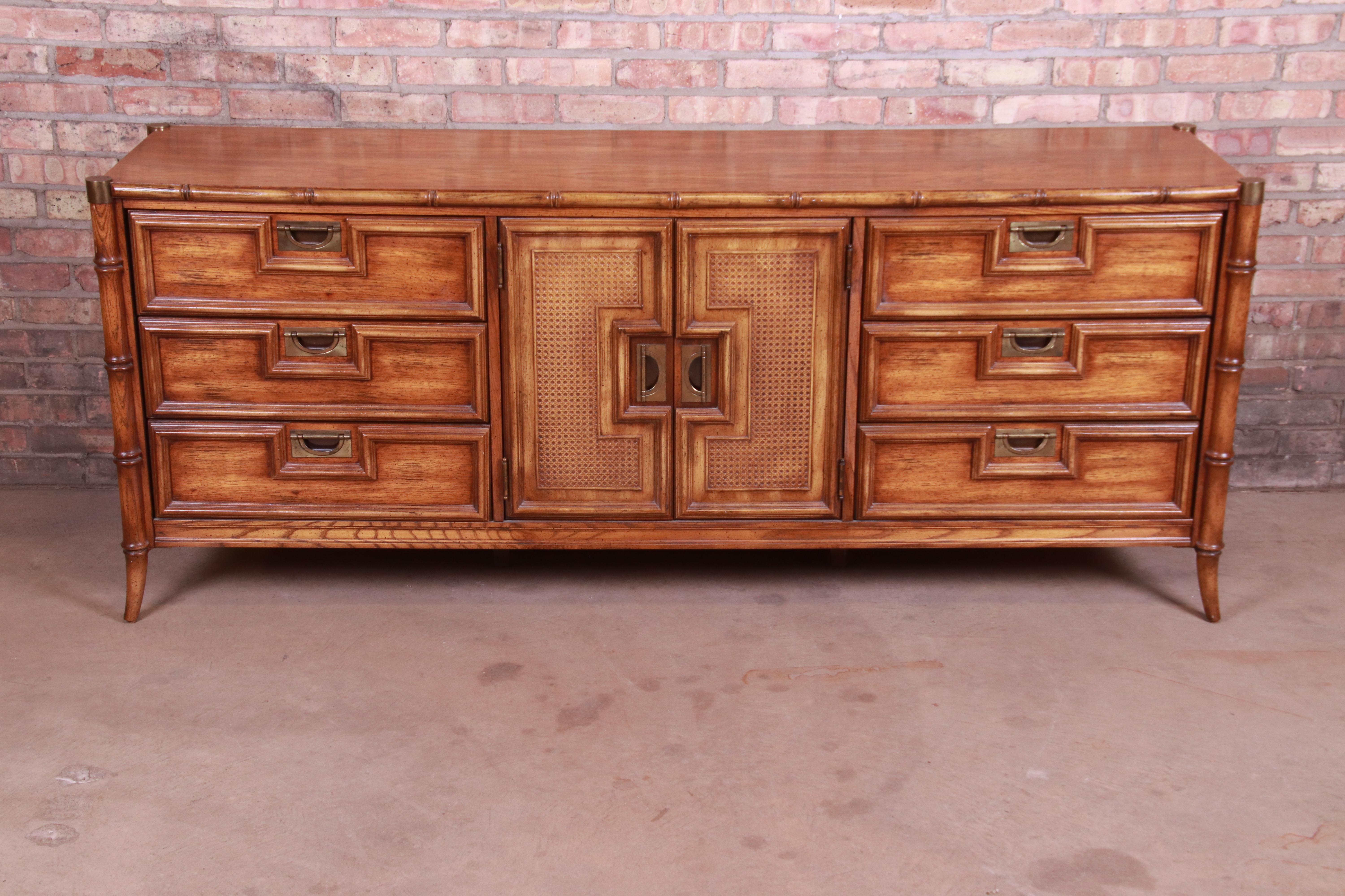 An exceptional Mid-Century Modern Hollywood Regency chinoiserie triple dresser or credenza

By Stanley Furniture

USA, circa 1960s

Walnut, with faux bamboo legs, cane front, and original brass hardware and accents.

Measures: 76.25
