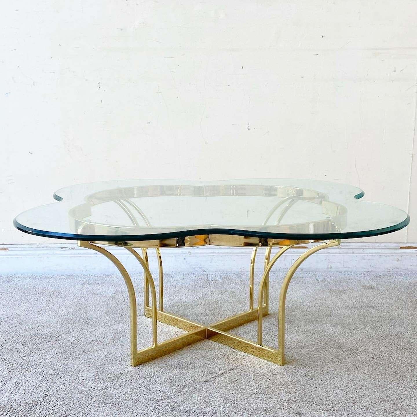 Amazing vintage Hollywood regency coffee table. Features a sculpted 4 clover shaped glass top with a gold metal base.