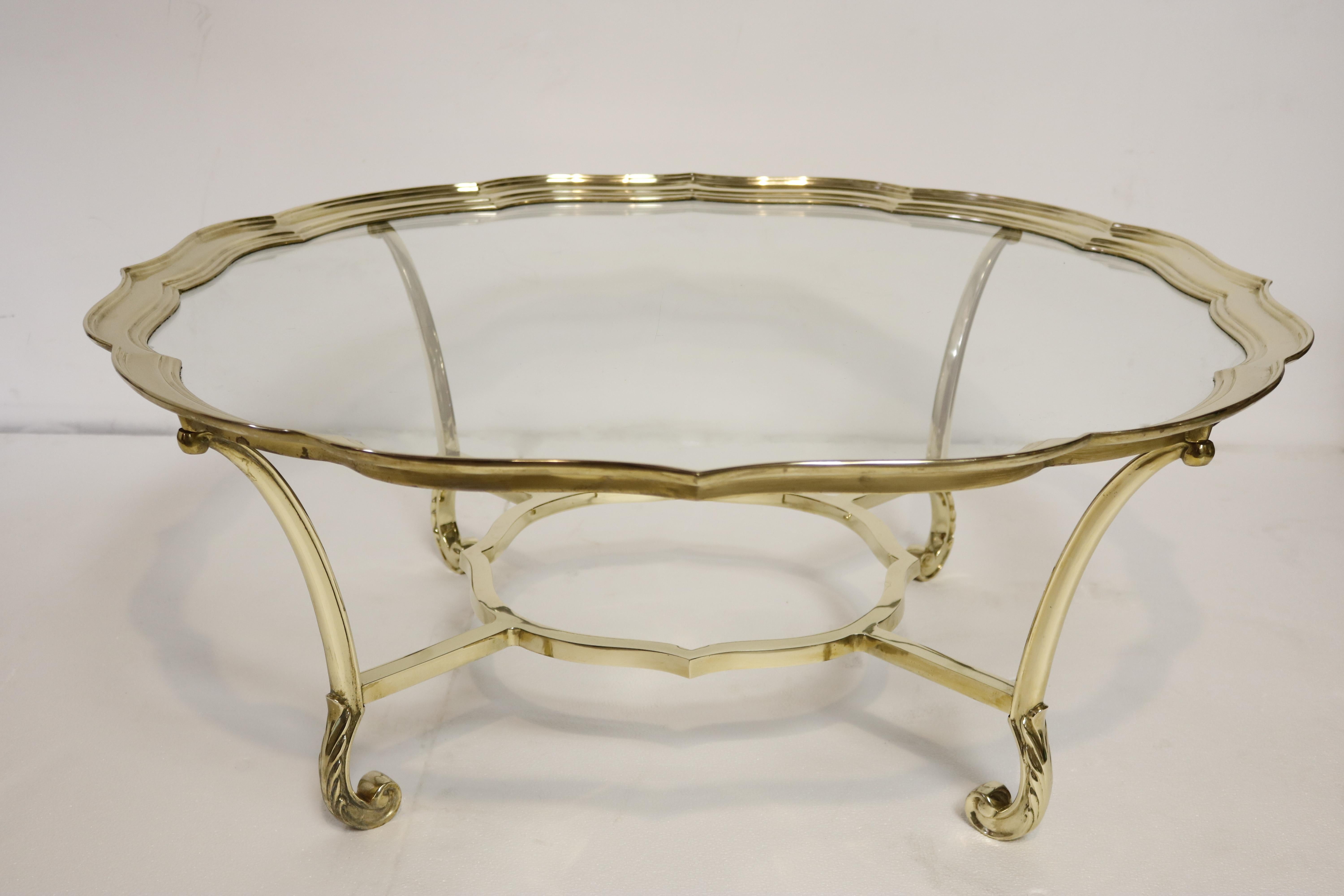 Elegant brass coffee table with glass top, with delicately ornate legs.