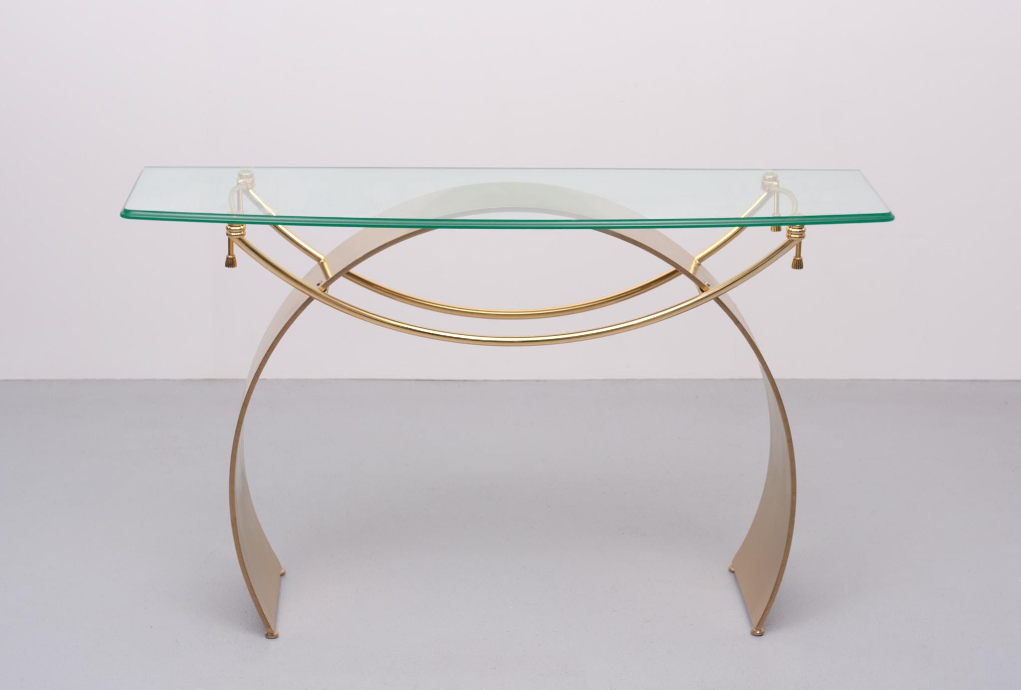 Love this Design. The curved Arch is made off Steel, In a Gold color. Curved 
Thick Glass top.Brass curved details. Hollywood Regency 1970s France.