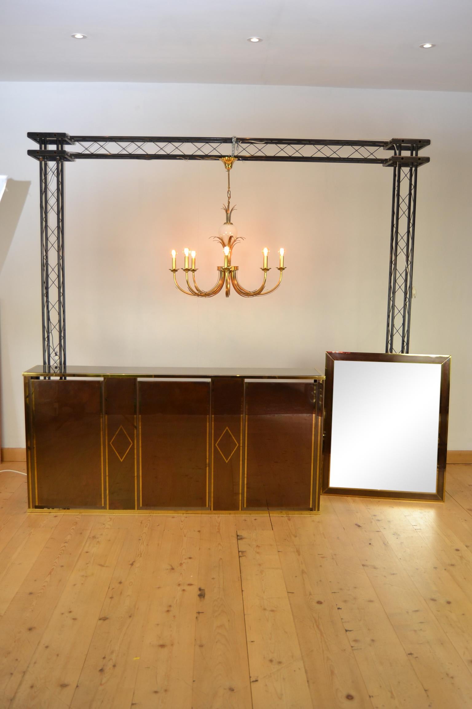 Hollywood Regency console table, dry bar, home bar or presentation table in the style of Belgo Chrome. This Stylish Piece of Furniture dates circa 1970s. 
It's made of brass or copper with a fume glass top.

Stylish wall table, console table. 

We