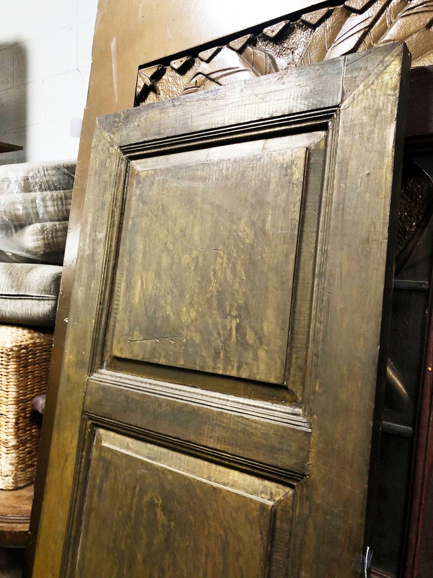 Large custom made Hollywood Regency brass wrapped solid oak door featuring sheets of copper that have been molded to the shaped of the door and held in place with brass nail heads. This one of kind door will bring a unique focal point to a doors