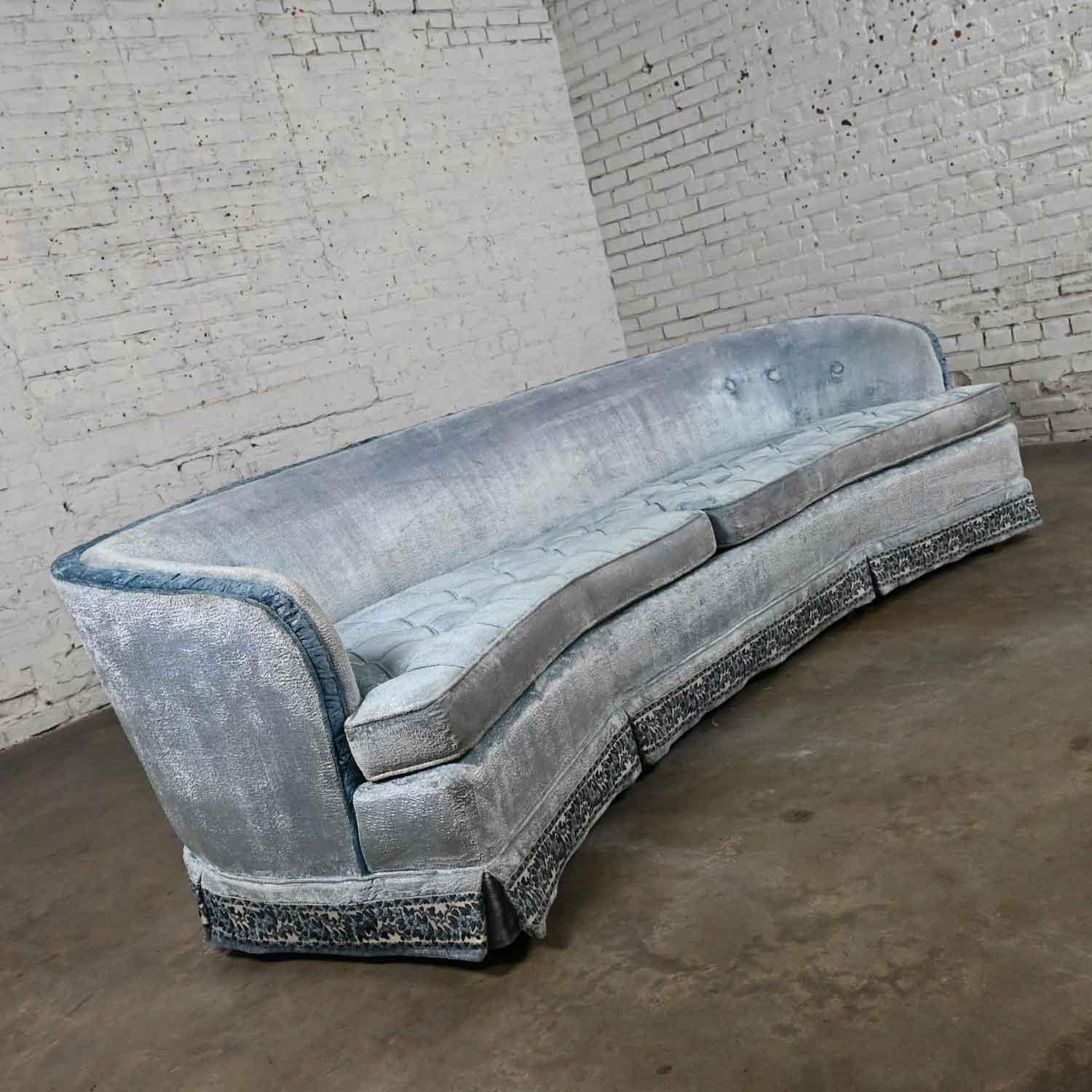 Lovely vintage Traditional or Hollywood Regency or Cottagecore curved kidney shaped blue velvet sofa by American of Martinsville. Comprised of 2 loose button tucked poly foam cushions, tight back with rouching, needlepoint ribbon trim skirt, and