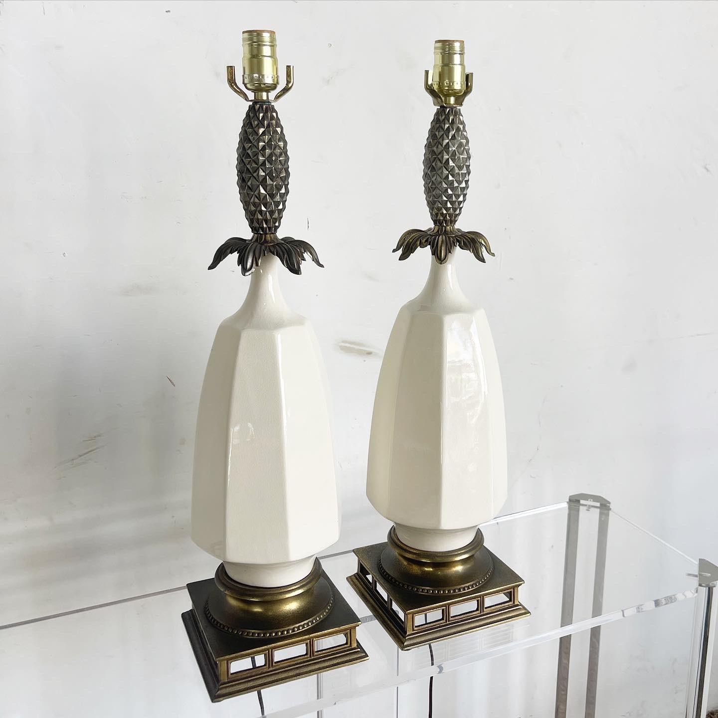 Elevate your home with the Cream Ceramic Brass Pineapple Table Lamps, a glamorous pair that captures the elegance of Hollywood Regency. Featuring a luscious pineapple shape with a delicate cream ceramic body and shiny brass accents, these lamps