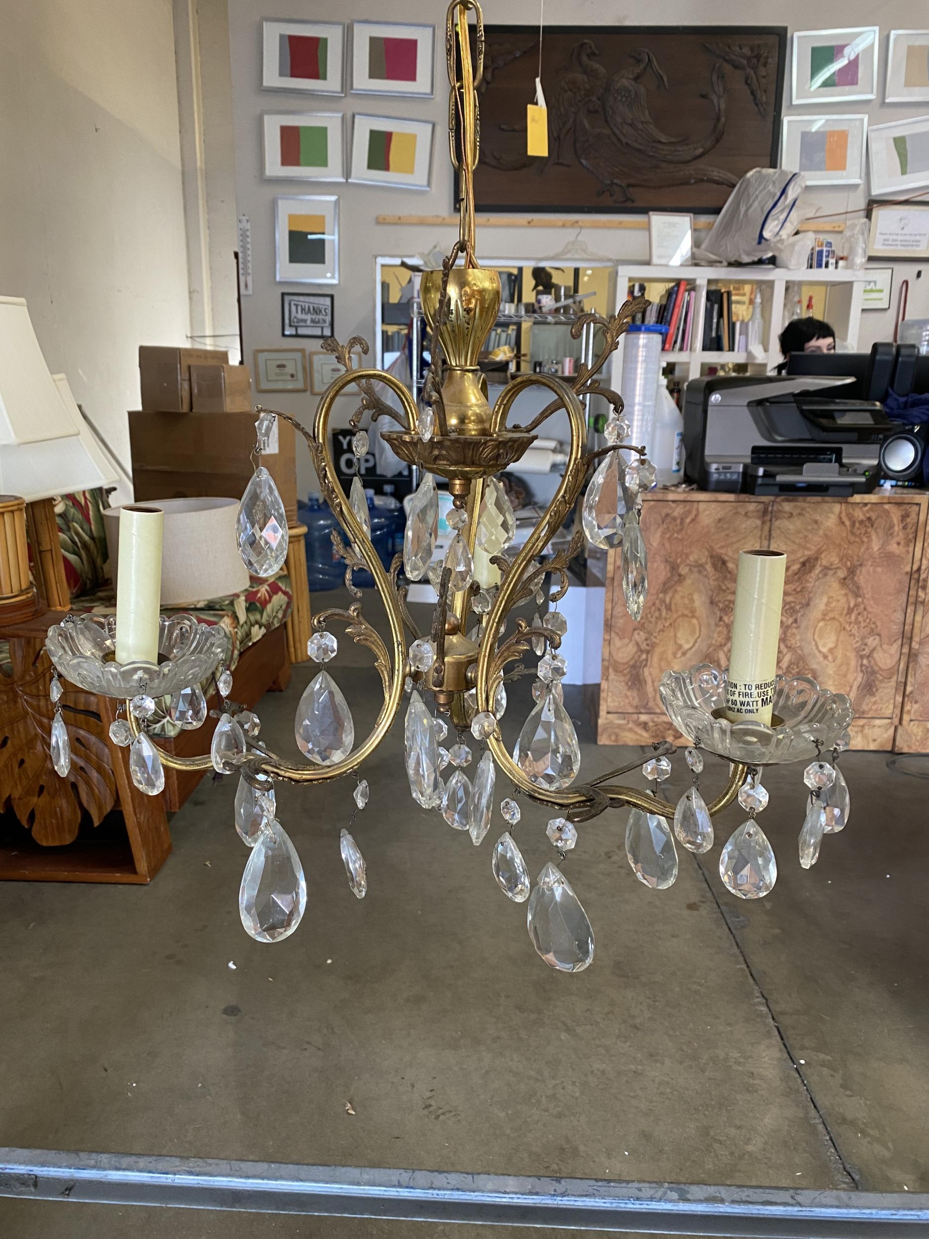 Un elegante lampadario in cristallo e ottone della Hollywood Regency del XX secolo. Questo lampadario ha tre luci che sono state elettrificate e circondate da cristalli scintillanti.

Misure: larghezza 18