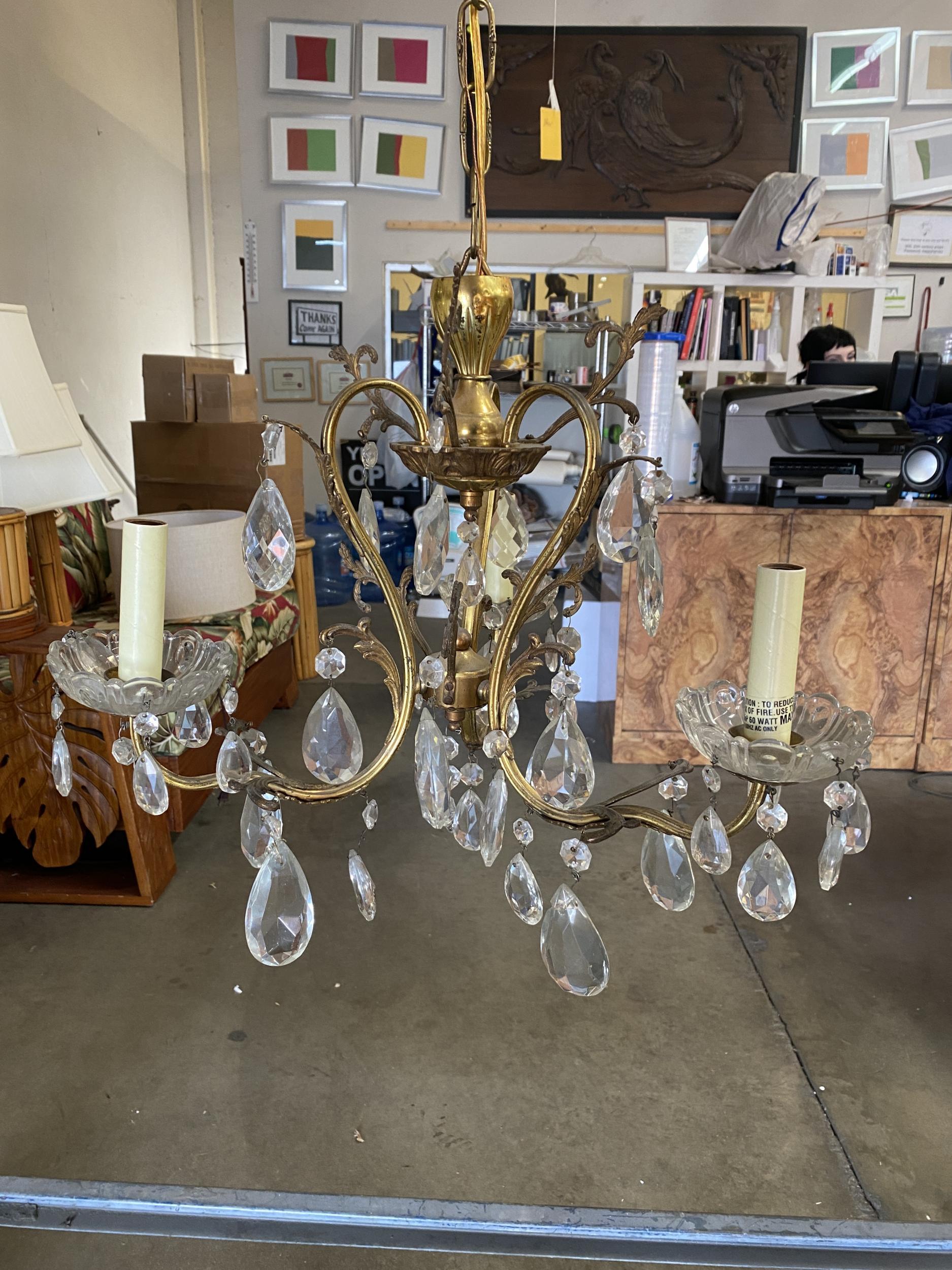 An elegant 20th Century Hollywood Regency crystal and brass chandelier. This chandelier has three light that have been electrified and surrounded with sparkling crystals

Measurement: width 18