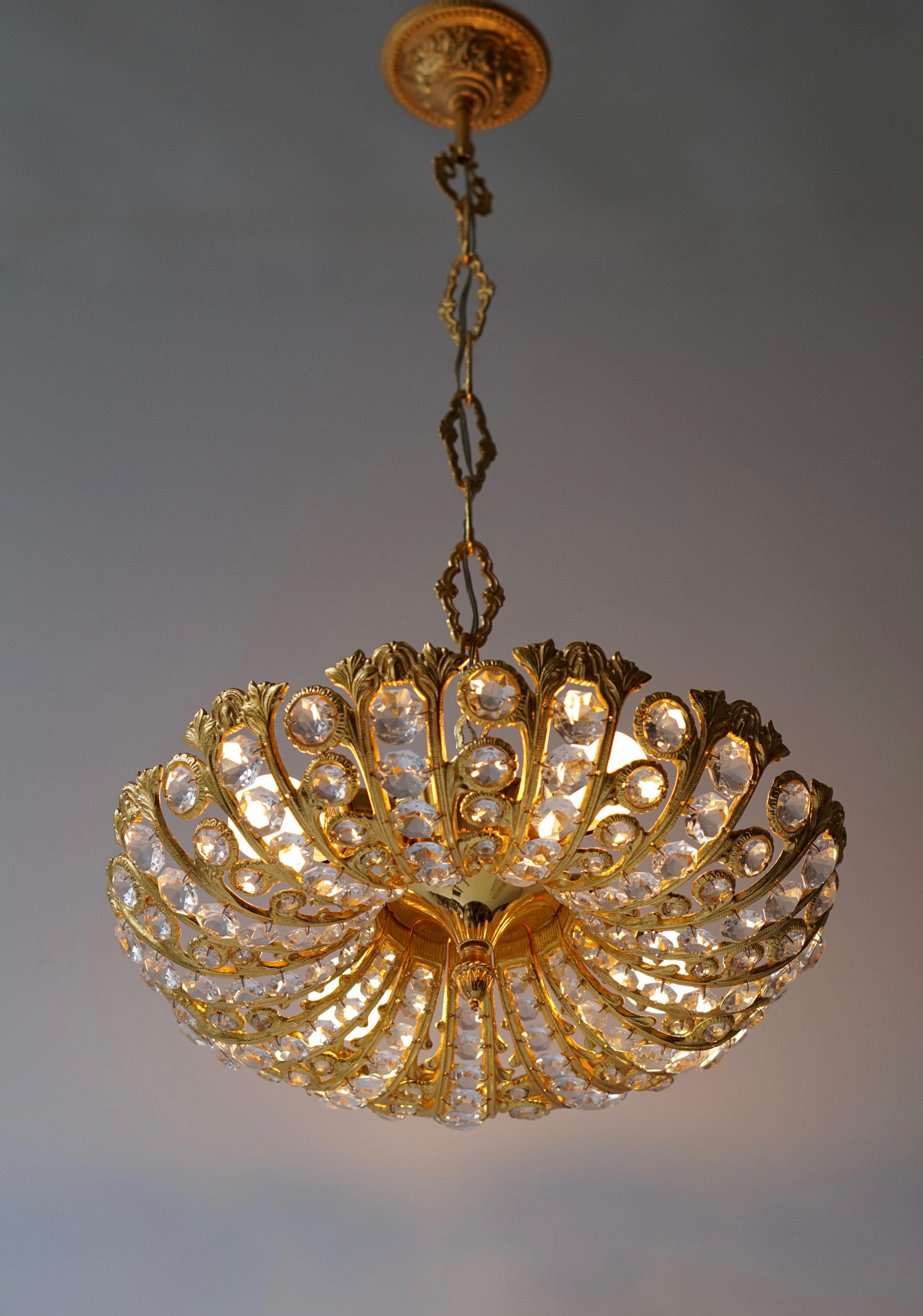Stunning Mid-Century Modern chandelier with gilded brass frame and cut crystal. 
Measures: Diameter 40 cm. Height fixture 18 cm. 
Total height including the chain 75 cm.