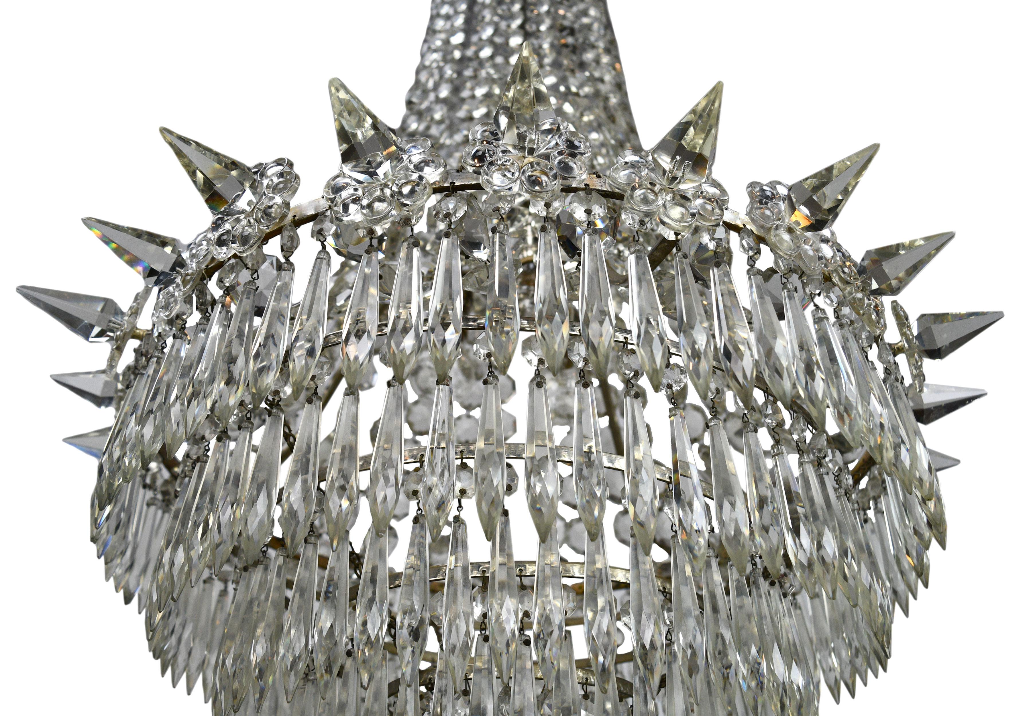 This stunning crystal chandelier features 6 rows of crystals and 24 uniquely shaped spikes adorning the circumference. The copious amount of individual crystals and crystal swag give this chandelier a wonderful golden glimmer when illuminated.