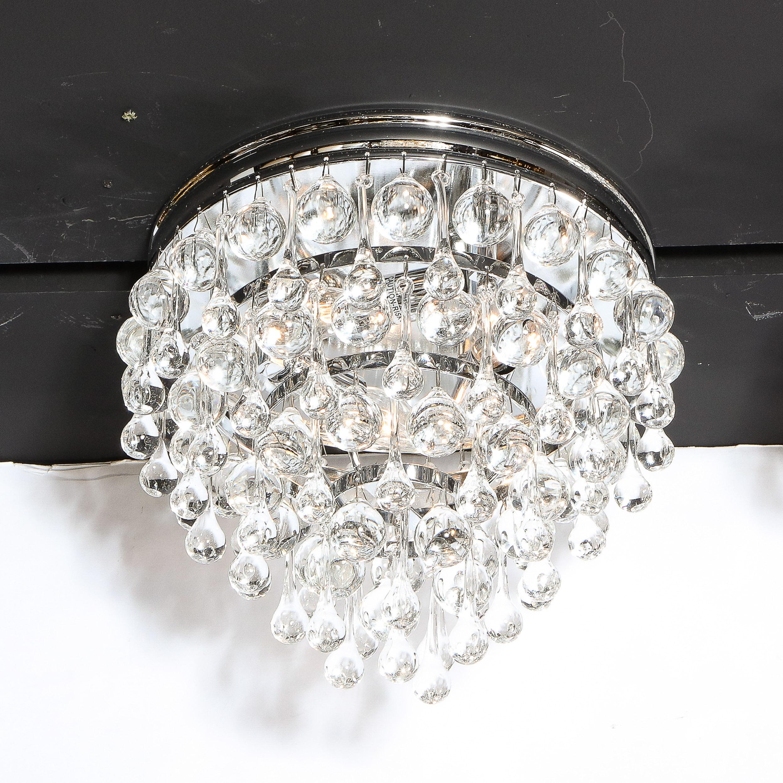 This stunning Hollywood Regency crystal teardrop flush mount chandelier features an abundance of hanging translucent glass tear drops suspended from a polished chrome frame consisting of six graduated concentric circular rows- imbuing the piece with