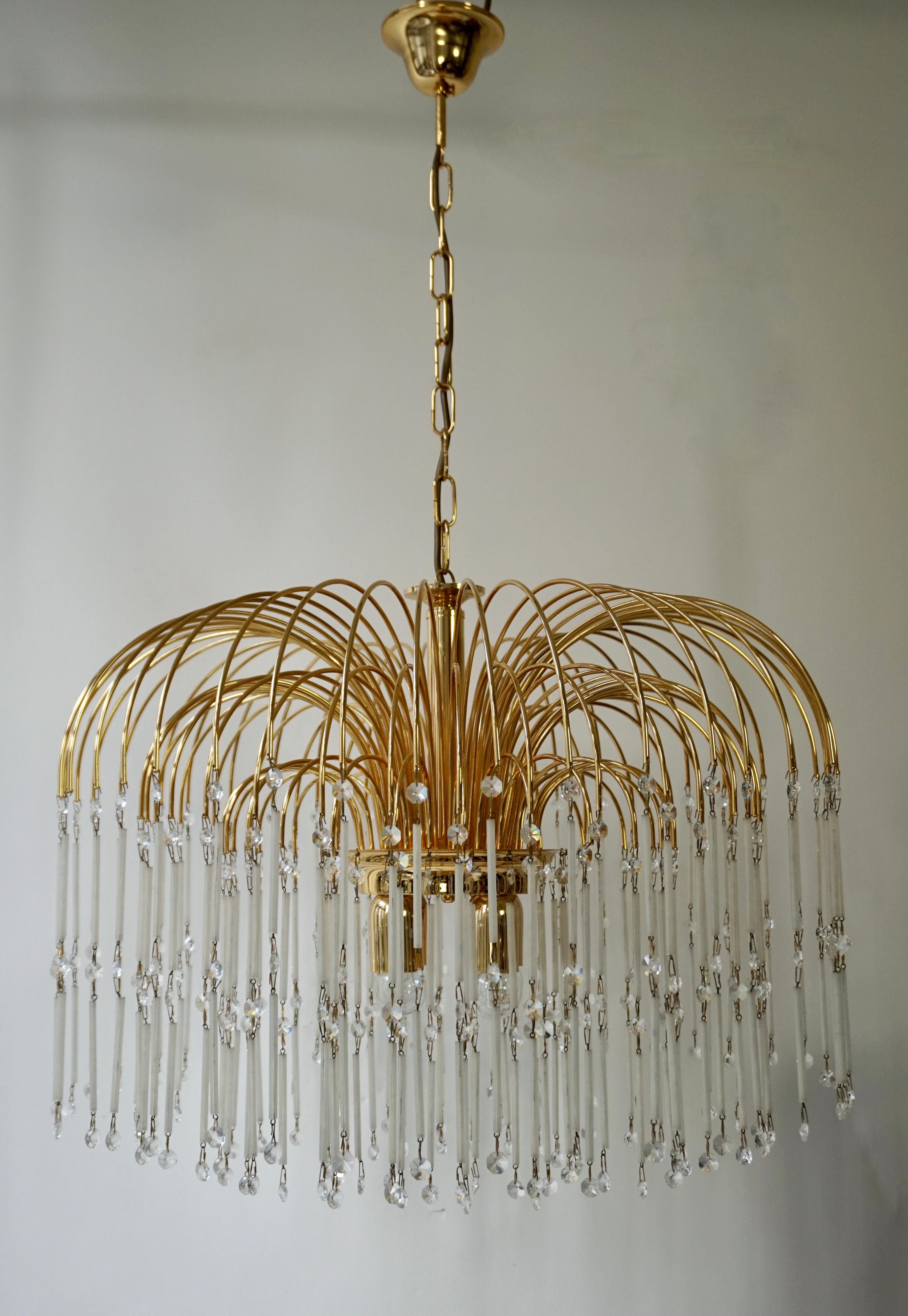 Mid-Century Modern waterfall chandelier with spectacular cut crystals throughout. Features a brass frame with multiple cascading tiers, fitted with of suspended glass tubes and crystal beads. The frame is comprised of three-tier in varying diameters