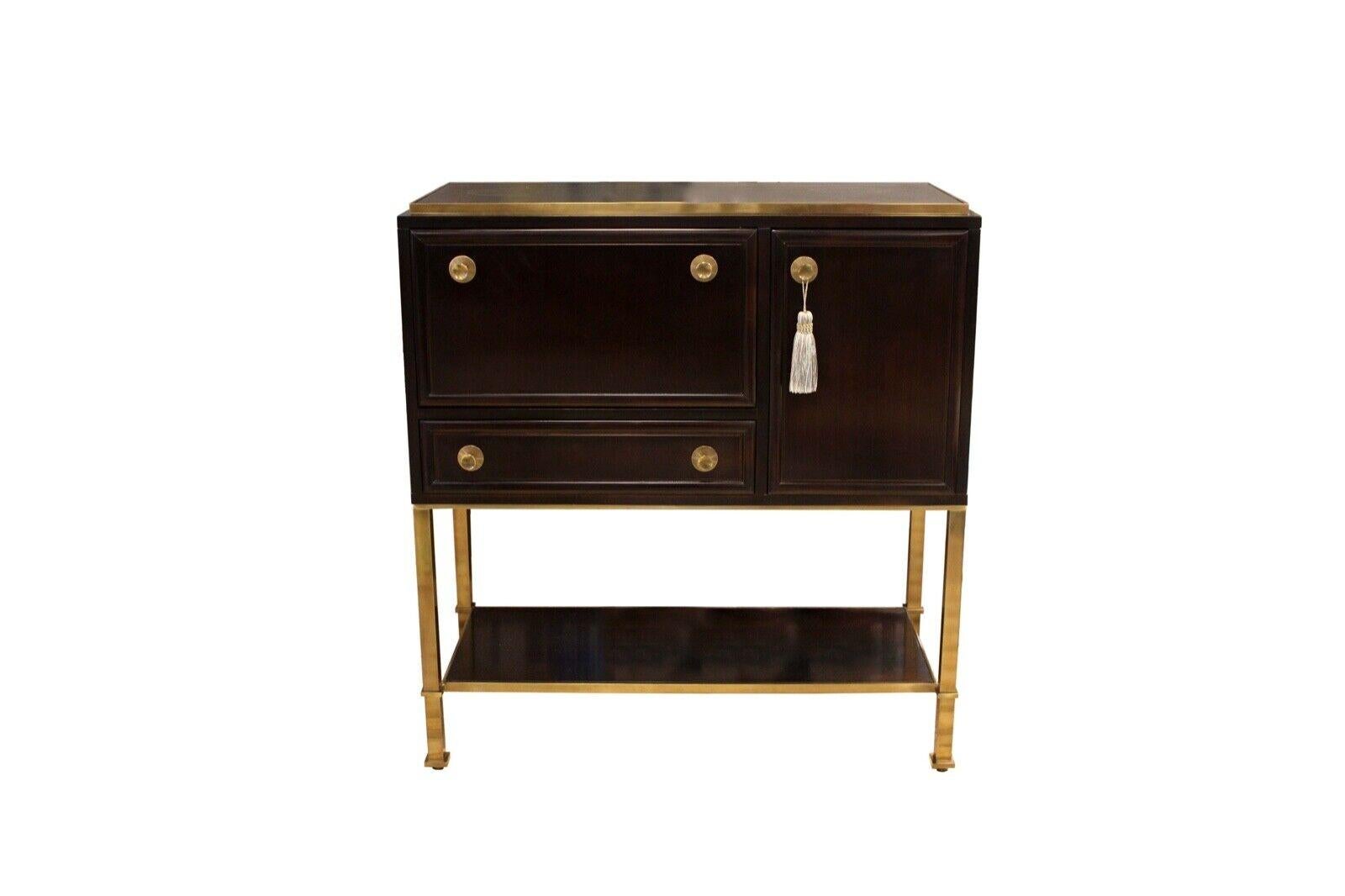 Le Shoppe Too presents a beautiful Baker Dansu Bar cabinet made of hardwood solid walnut & ebony veneer, brass hardware with polished bronze finish. One drop lid with mirror on case back panel. One drawer with liner. One door with adjustable shelf.