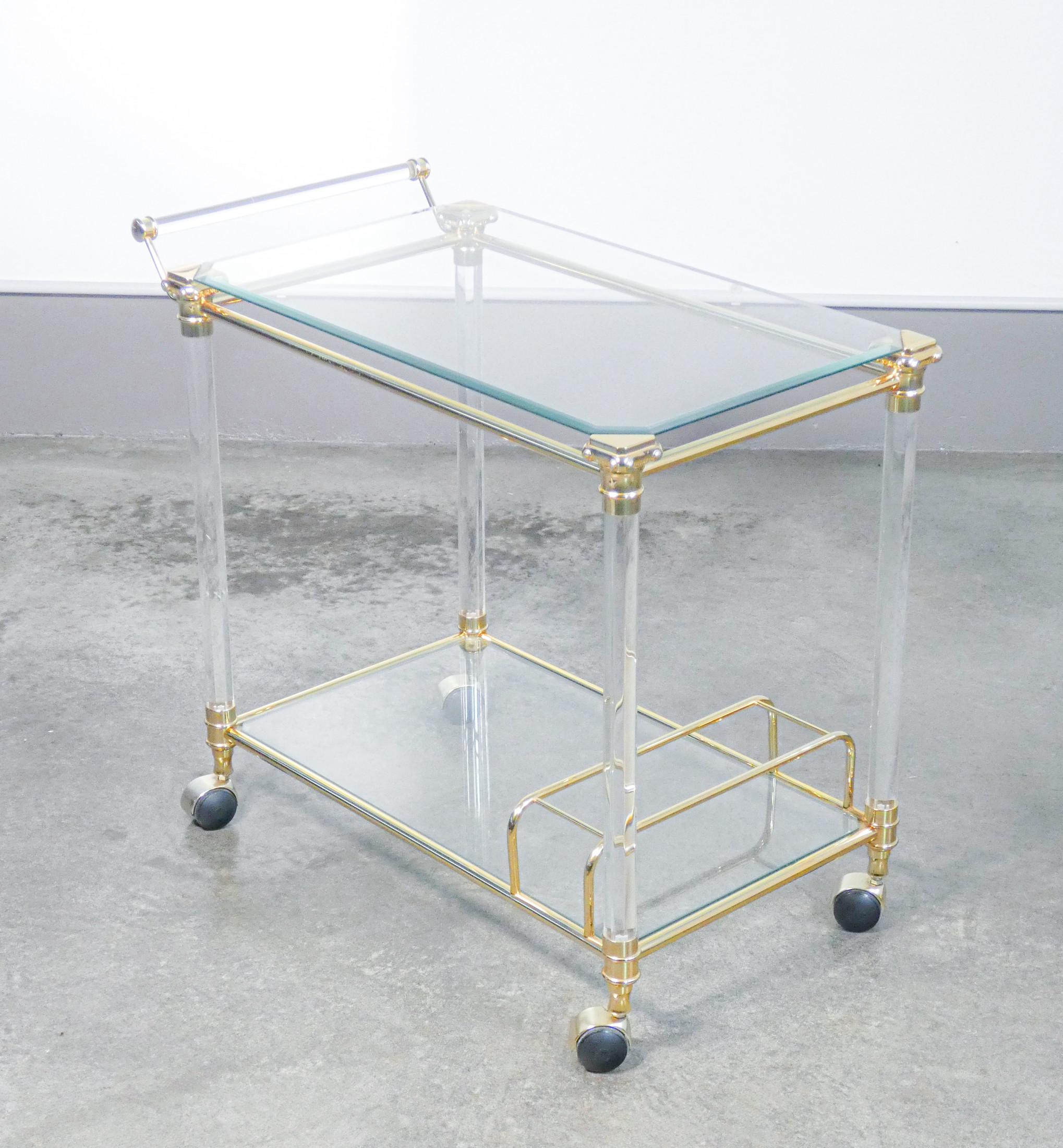 Hollywood Regency design
servign trolley,
in gilded metal, glass and plexi

Period
70s / 80s

Template
Serving trolley with wheels and two shelves

Materials
Golden metal, glass tops, columns and handle in plexi

Dimensions
Top 70 x 44