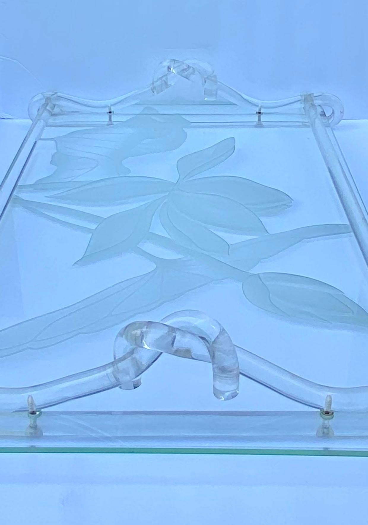 Hollywood Regency Dorothy Thorpe frosted glass and lucite tray, mid-20th century. Rectangular tray with intaglio-etched floral lily pad floral decoration and intertwined lucite pretzel form rod handles.

Marked with Dorothy C Thorpe initials “dTc”