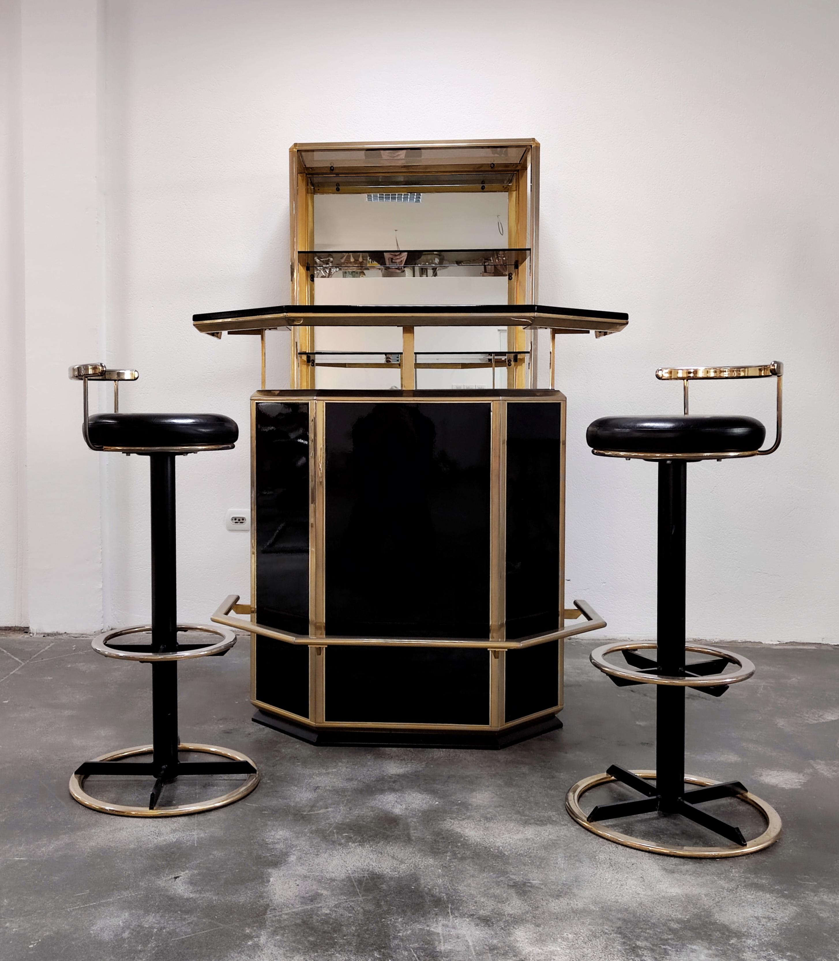 In this listing you will find a spectacular Hollywood Regency dry bar set, consisting of dry bar counter, two bar stools and the mirrored shelf for bottles and glasses. This high quality set is done in black lacquer wood, glossy and reflective,