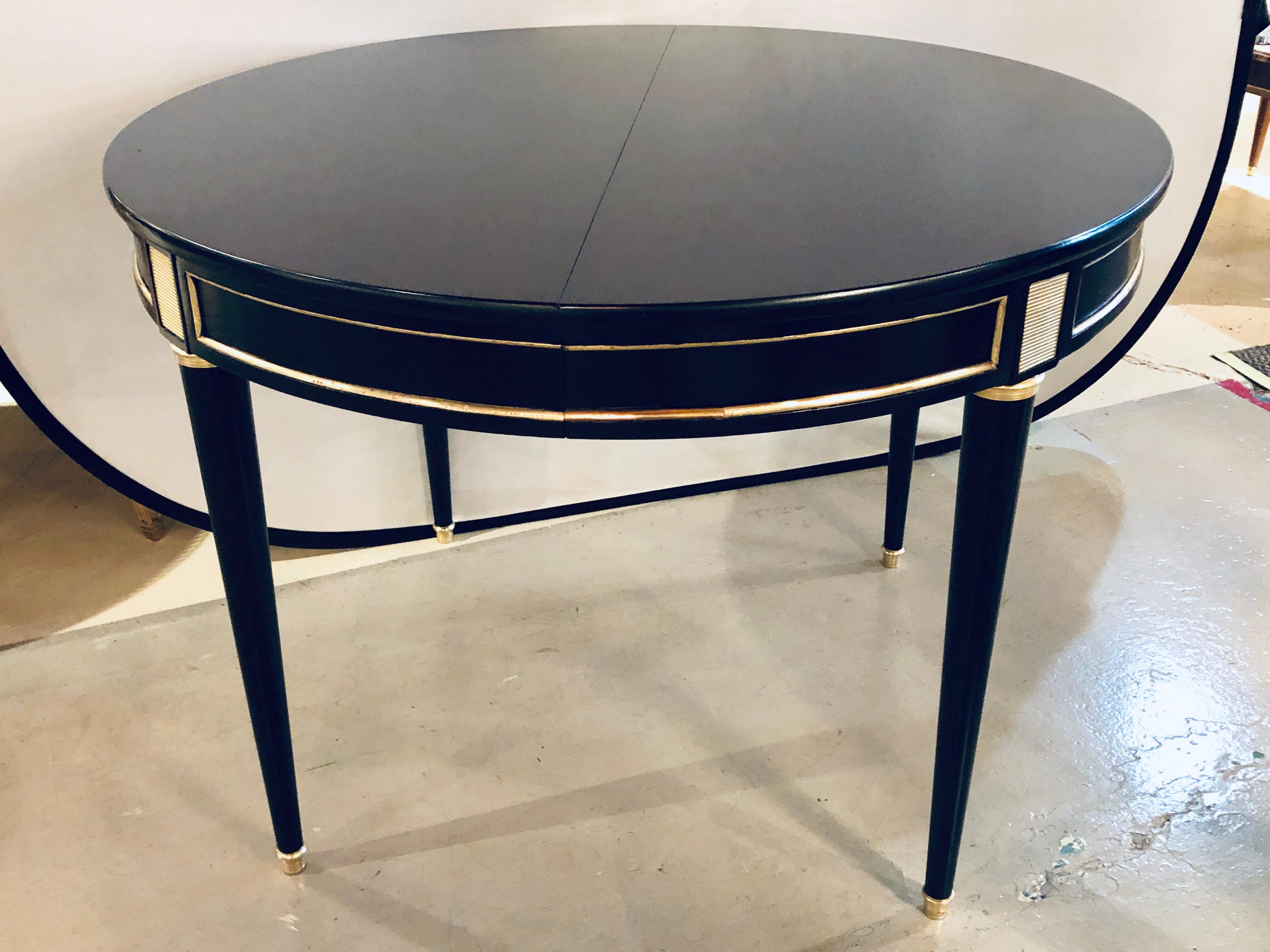 This is a stunning Hollywood Regency ebonized Maison Jansen style bronze mounted dining table which has three twenty inch table extension leaves one fully skirted. The Louis XVI style sleek and stylish legs having bronze sabots and capitals