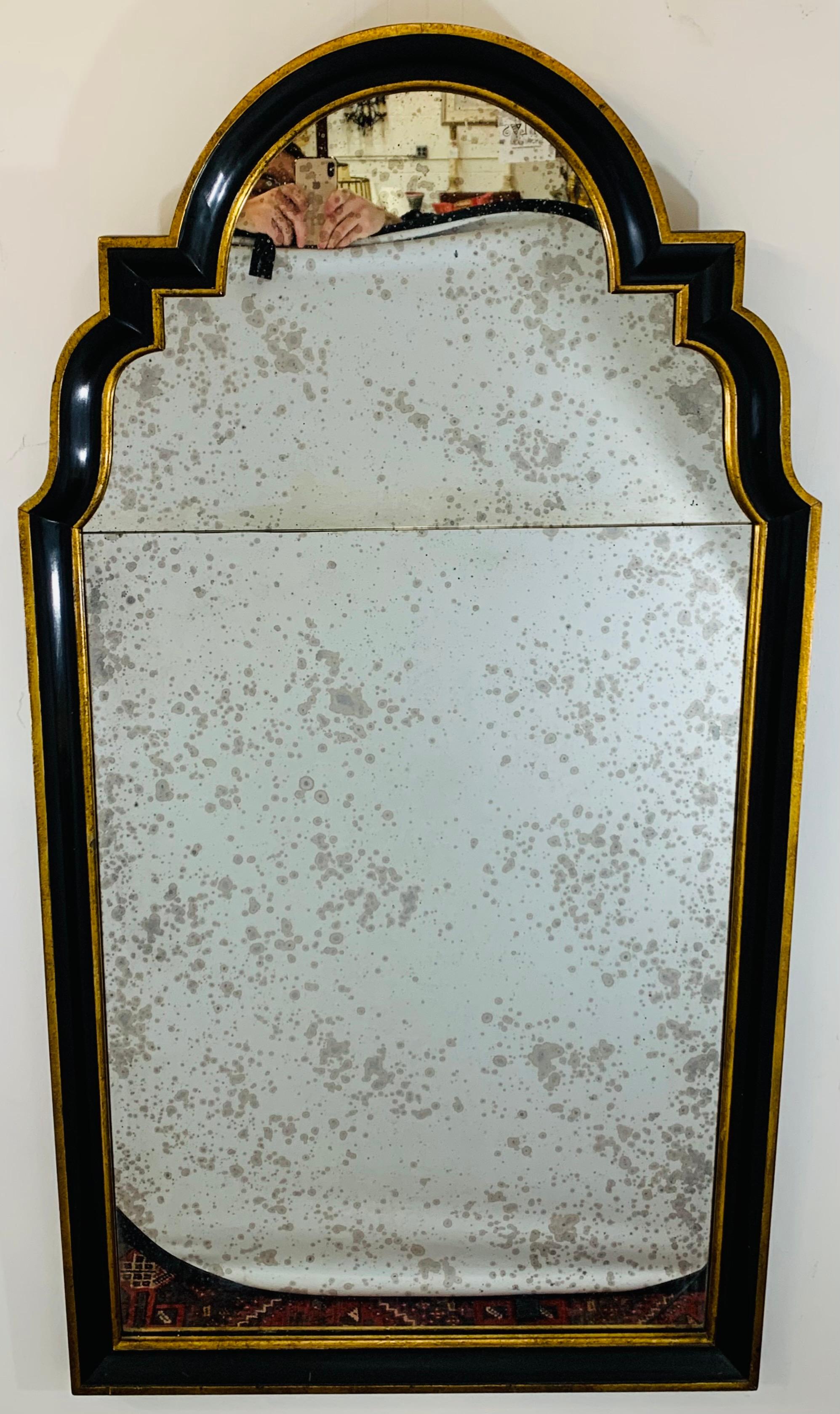 A stunning antiqued glass mirror Hollywood Regency wall , mantel or console mirror in an ebony black and finely hand painted with gold lines shaping the mirror frame. The arched design and overall versatile style of the mirror is classy and will add