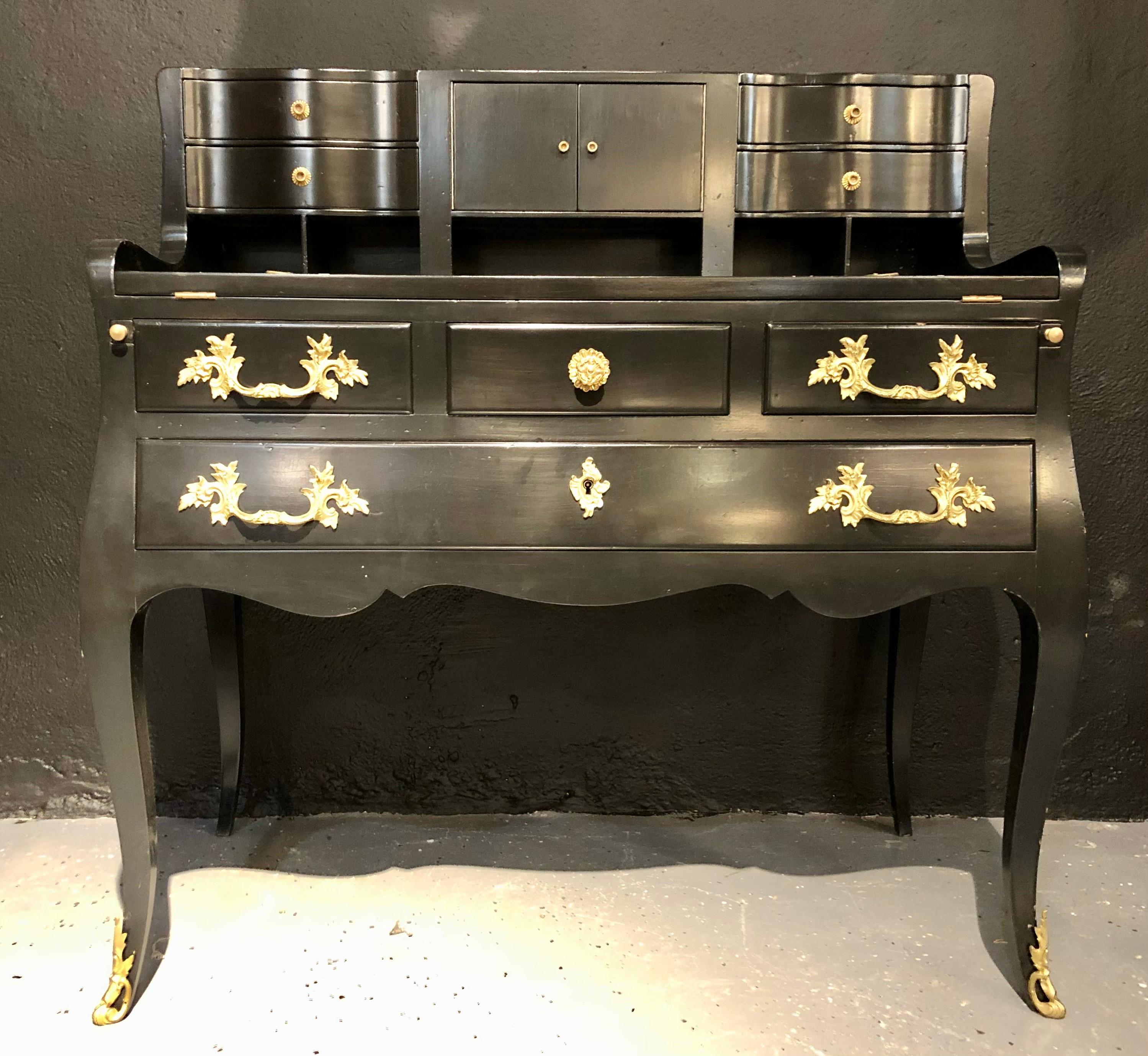 Hollywood Regency ebony ladies desk. Finley crafted Louis XV style stamped Jansen flip front desk having sleek and slender legs supporting a lager center drawer flanked by smaller side drawers all with bronze pulls. The top portion having a brown