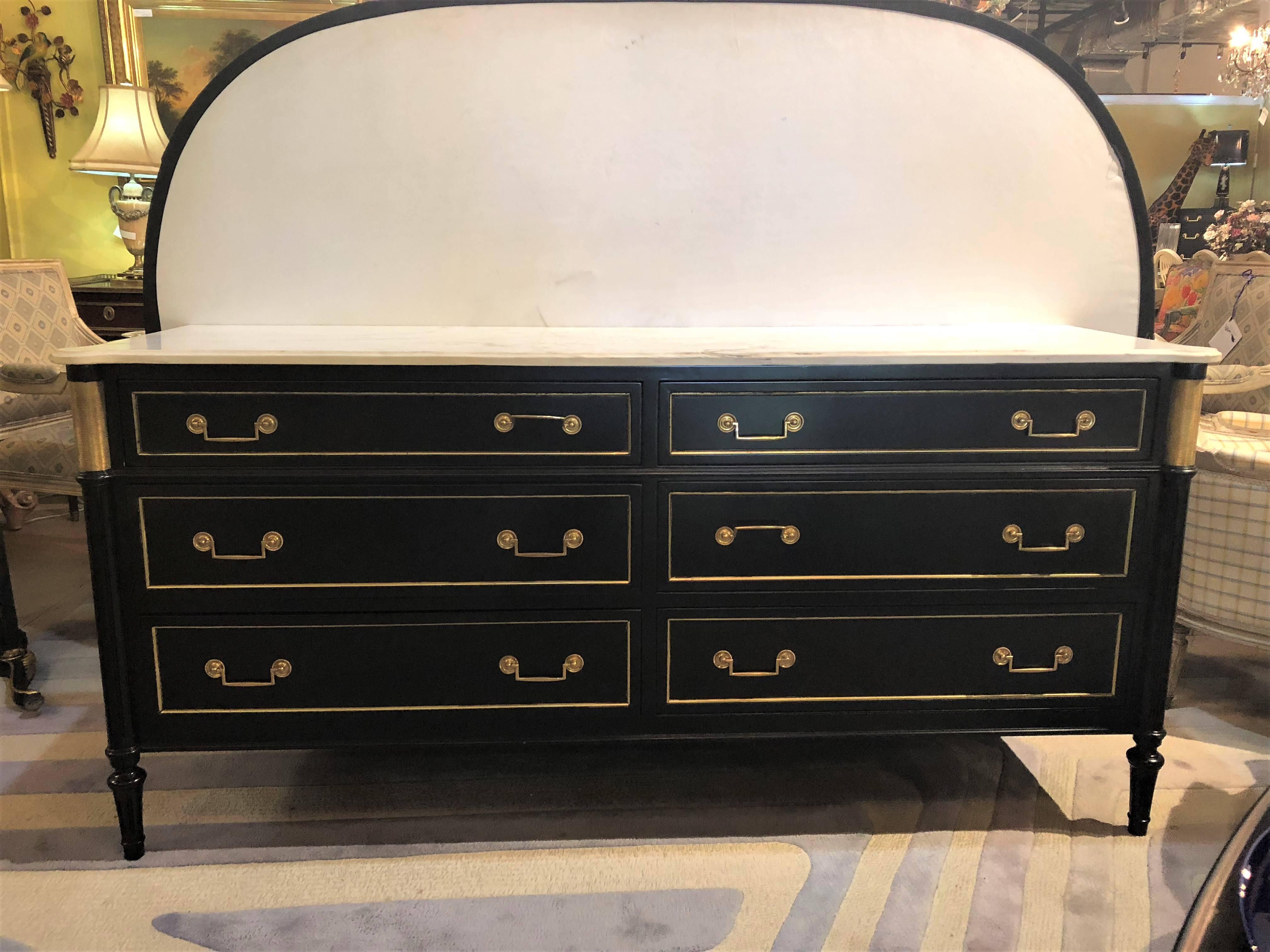 A Hollywood Regency ebony Maison Jansen Louis XVI style dresser or chest. This fine three by three bronze framed dresser or server has bronze cookie cutter corners and reeded corners on all sides. The whole supporting a white marble top with double