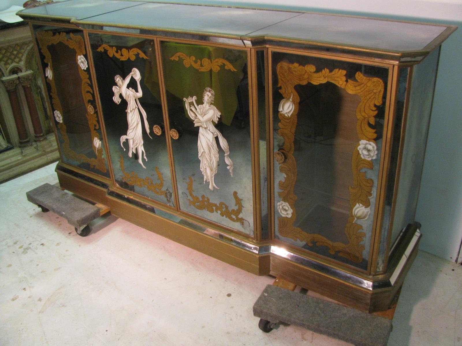 Fabulous mirrored cabinet which can used as a sideboard, buffet or as a total bar. Centre top panel opens to reveal a mirrored work space and a mirrored well for bottles. Centre doors with Églomisé decoration open for storage. Side doors framed with