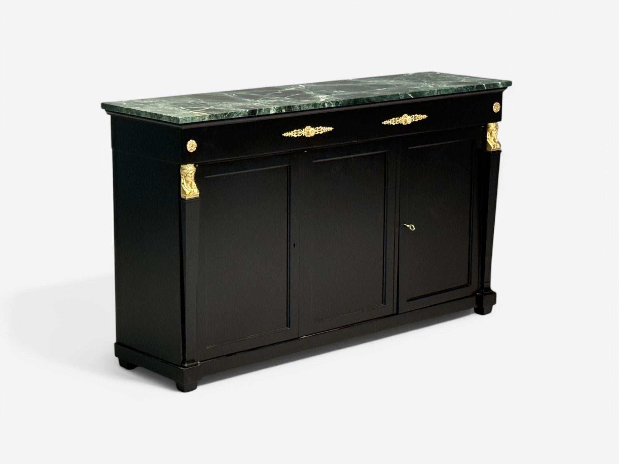 Hollywood Regency, Estilo Imperio, Madera Negro Satinado, Bronce, Mármol Verde, Credenza, Década de 1940

Un sofisticado aparador con una encimera de mármol verde y blanco sobre una base de ébano pulido con finas monturas de bronce. El marco de
