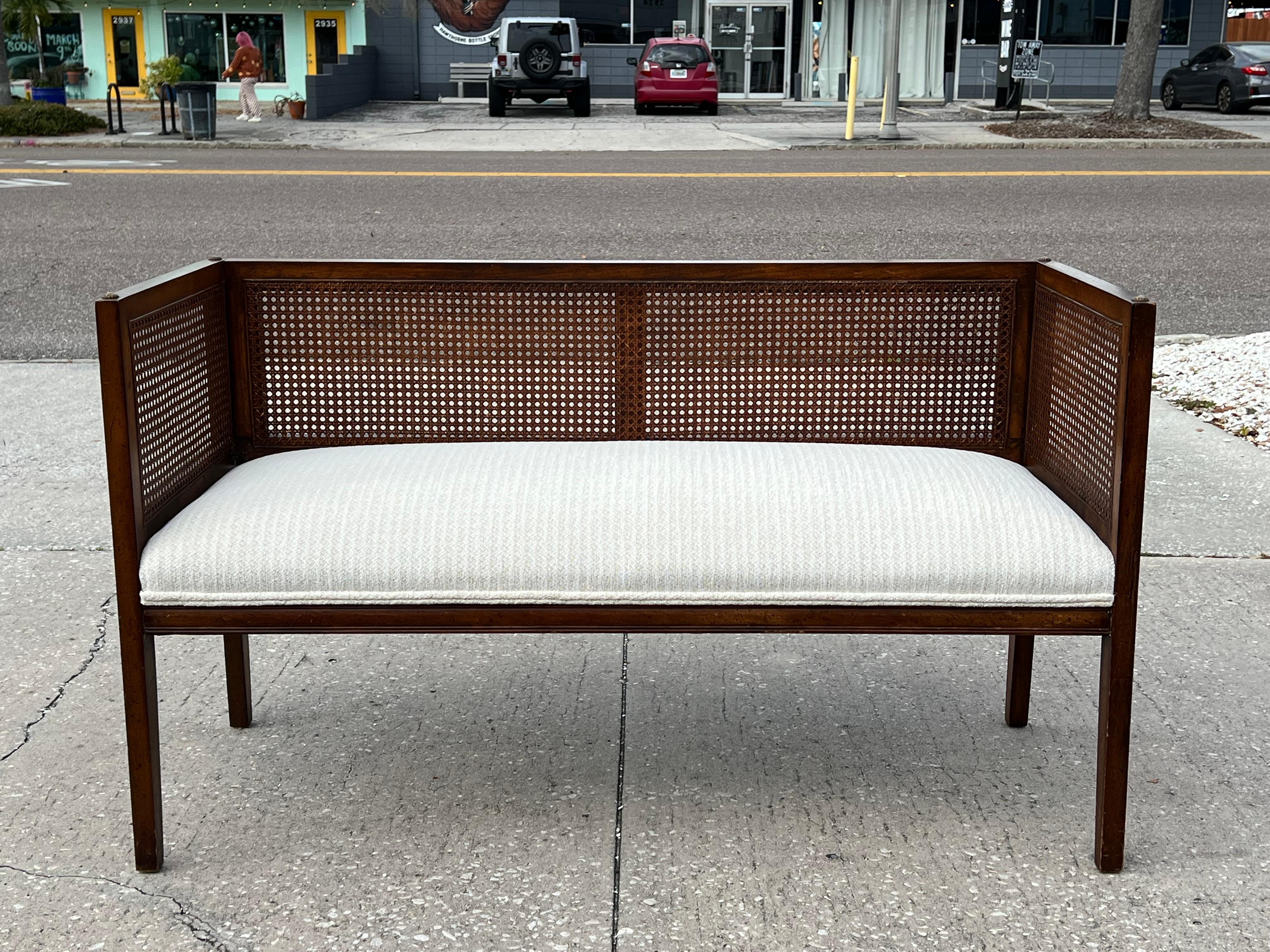 A classic enryway bench in Hollywood Regency style. Caned and upholstered seat. Original 1950's speckled finish. Reupholstered.