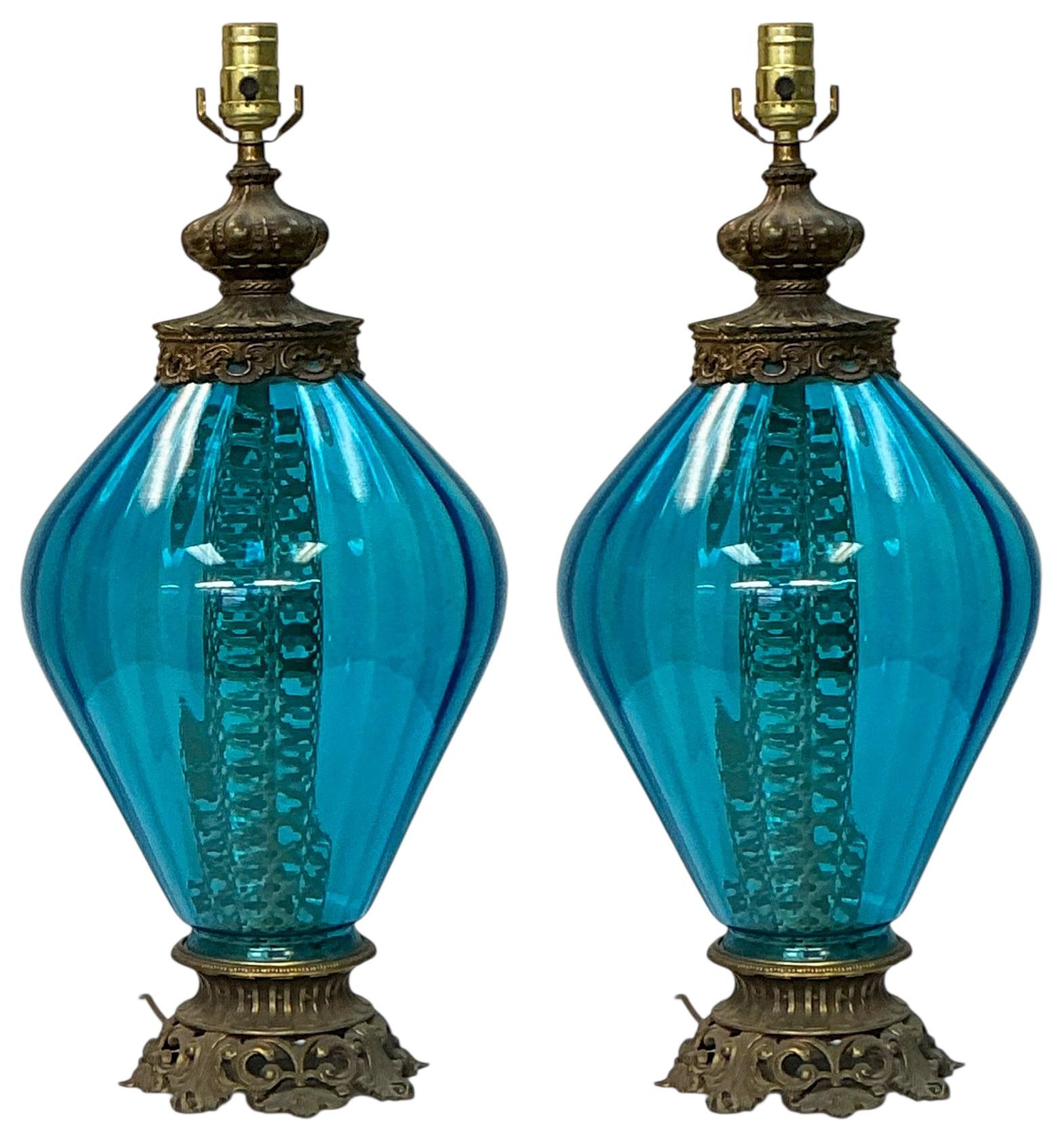Si tratta di una bellissima coppia di lampade da tavolo in vetro blu e ottone dell'epoca Hollywood Regency. Il cablaggio è buono e presenta un interruttore a tre vie. Non sono contrassegnati.