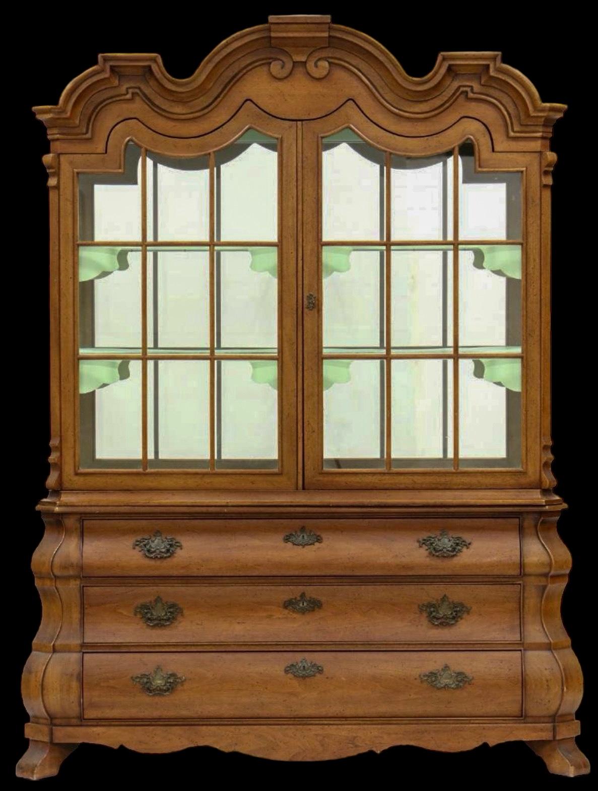 This glazed walnut cabinet was designed by Dorothy Draper for Henredon as part of her Viennese Collection. It has Dutch styling with its highly stylized styling and bombe base. The interior is a seafoam color with mirrored back. It is in very good