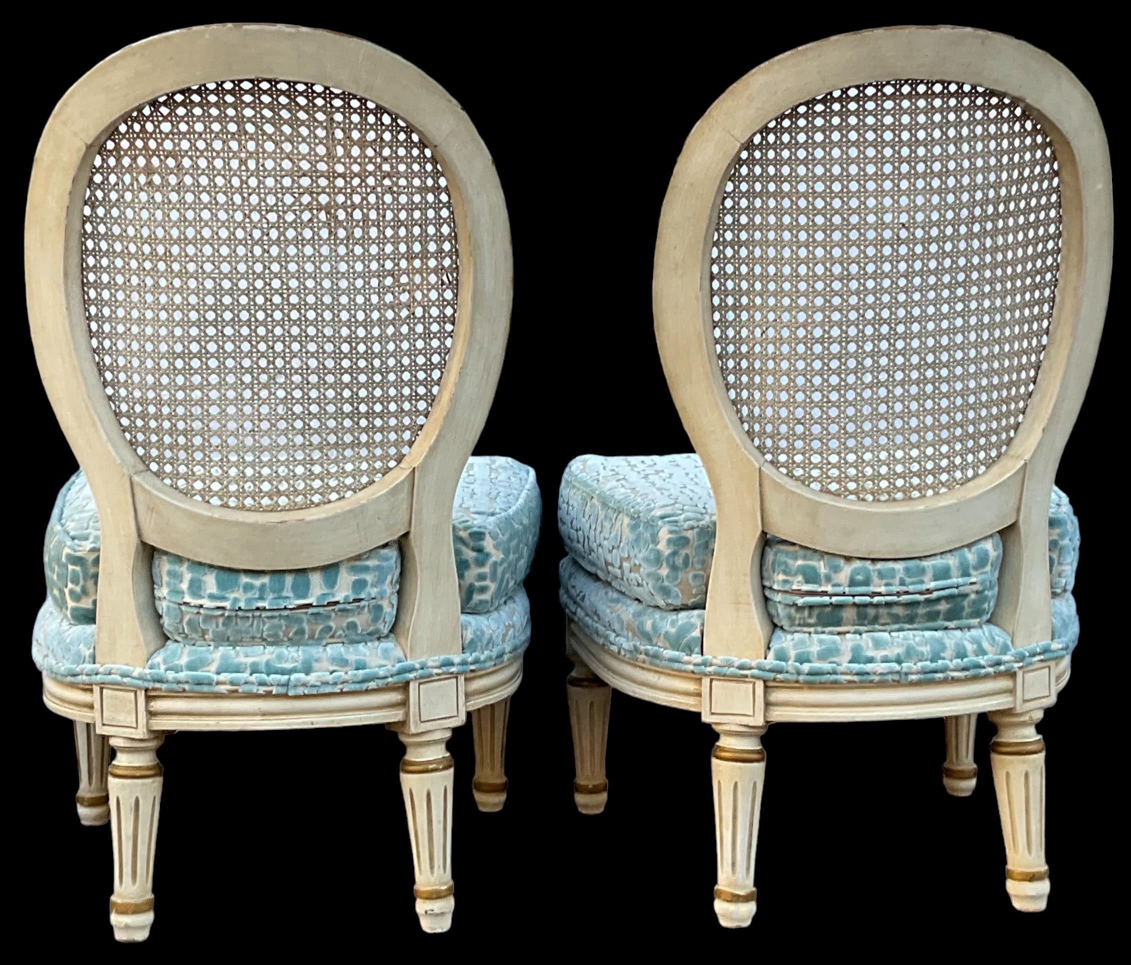 This is a pair of Hollywood Regency Era Italian slipper chairs newly upholstered in a cut velvet. The frame is an ivory paint with gilt accents. The wood has a general wear. They are unmarked.