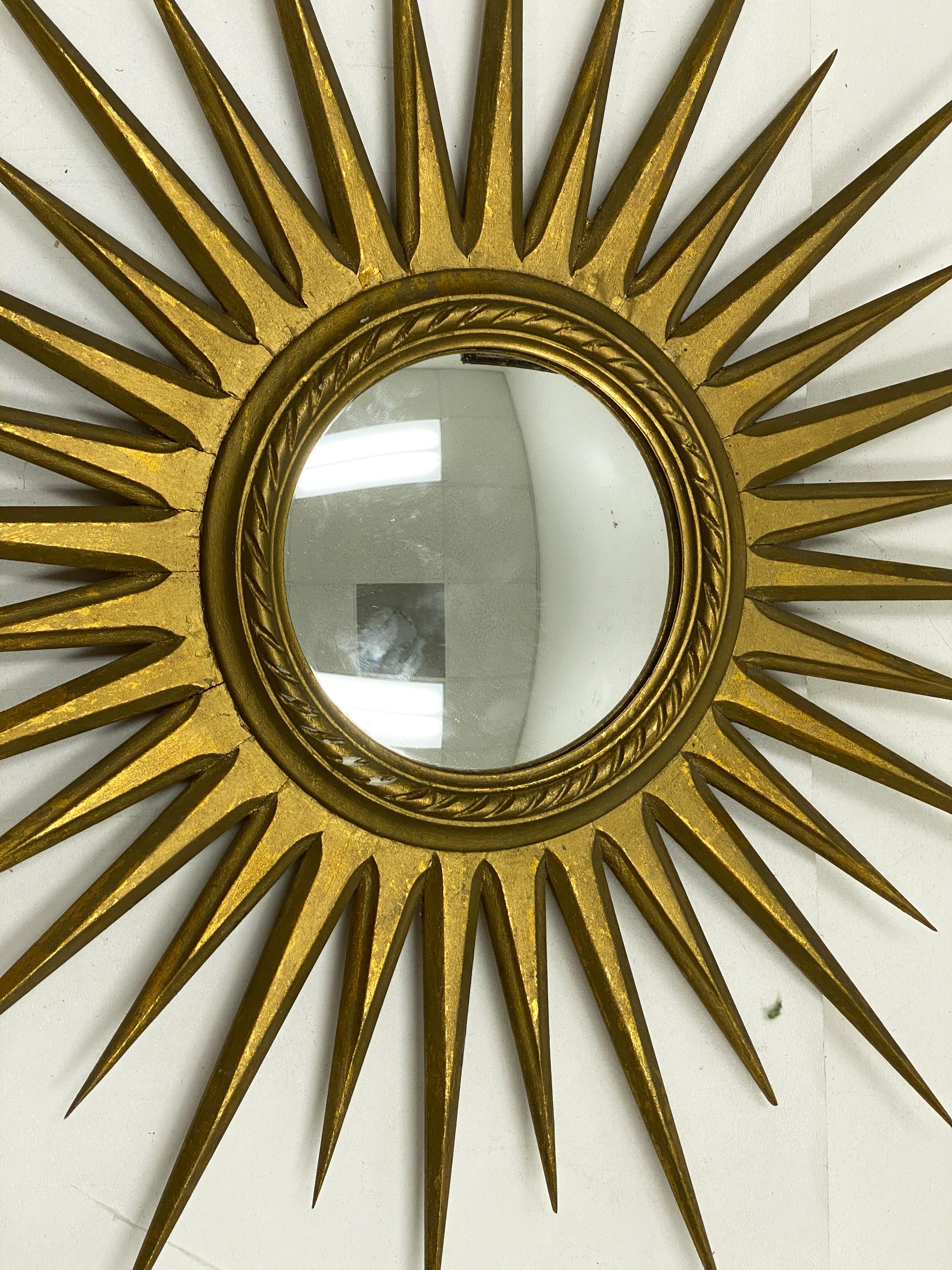 This is a midcentury Italian giltwood convex sunburst mirror. It dates to the 1960s and is unmarked.