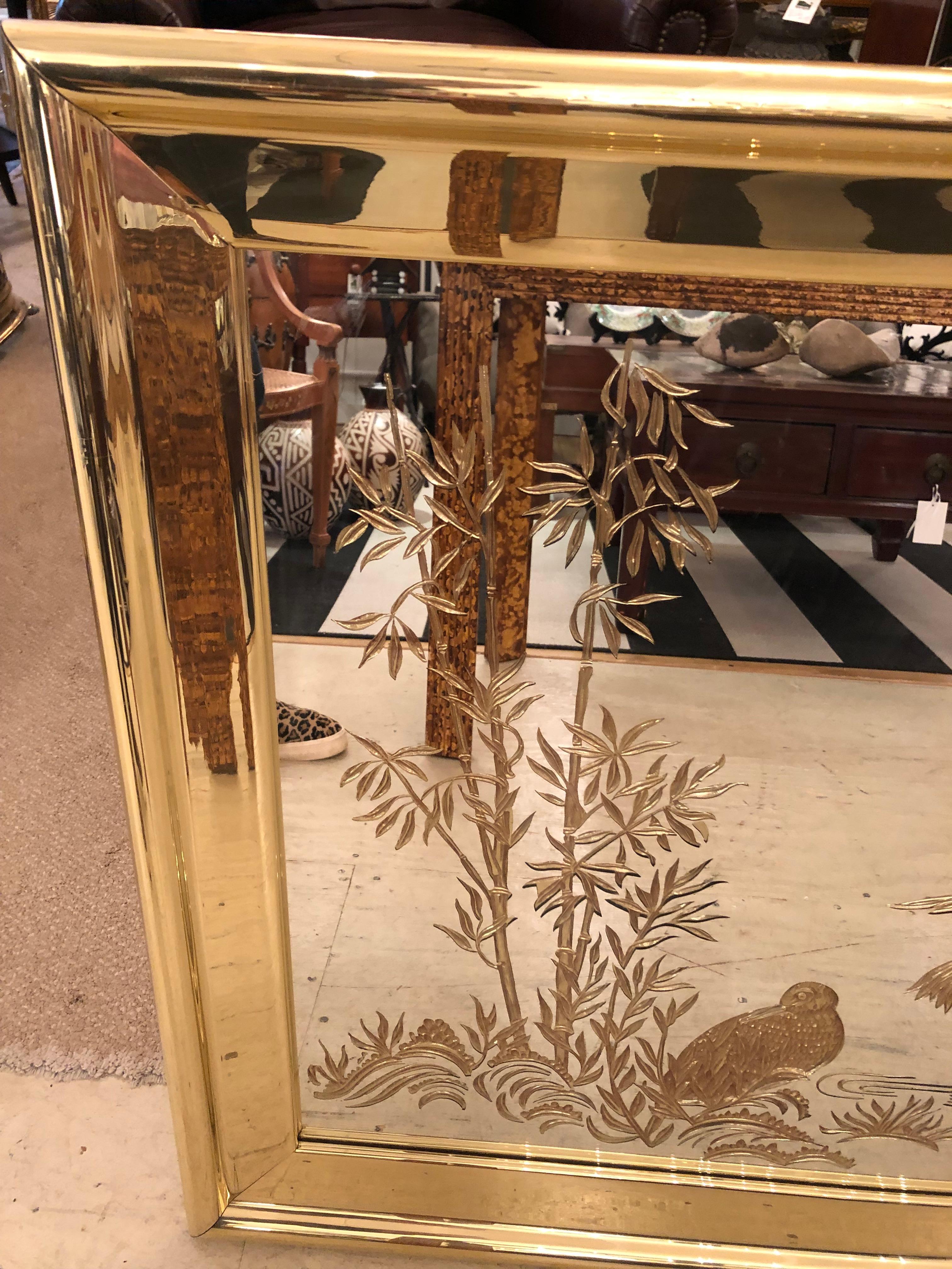 A large glamorous rectangular etched mirror having reverse eglomise gold decoration of cranes and Asian inspired landscape. Big gutsy brass frame adds a spicy touch.
