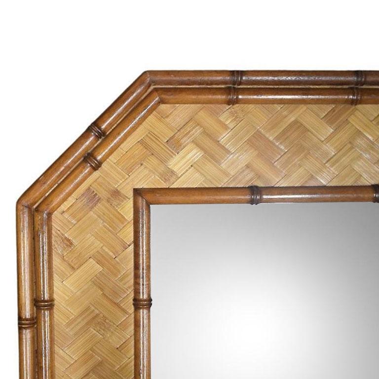 An octagonal faux bamboo and rattan wall mirror by American of Martinsville. A superb example of Hollywood Regency design, this mirror will be fabulous above a dresser, dressing table, or in a foyer, or bathroom. The mirror is rectangular and can be