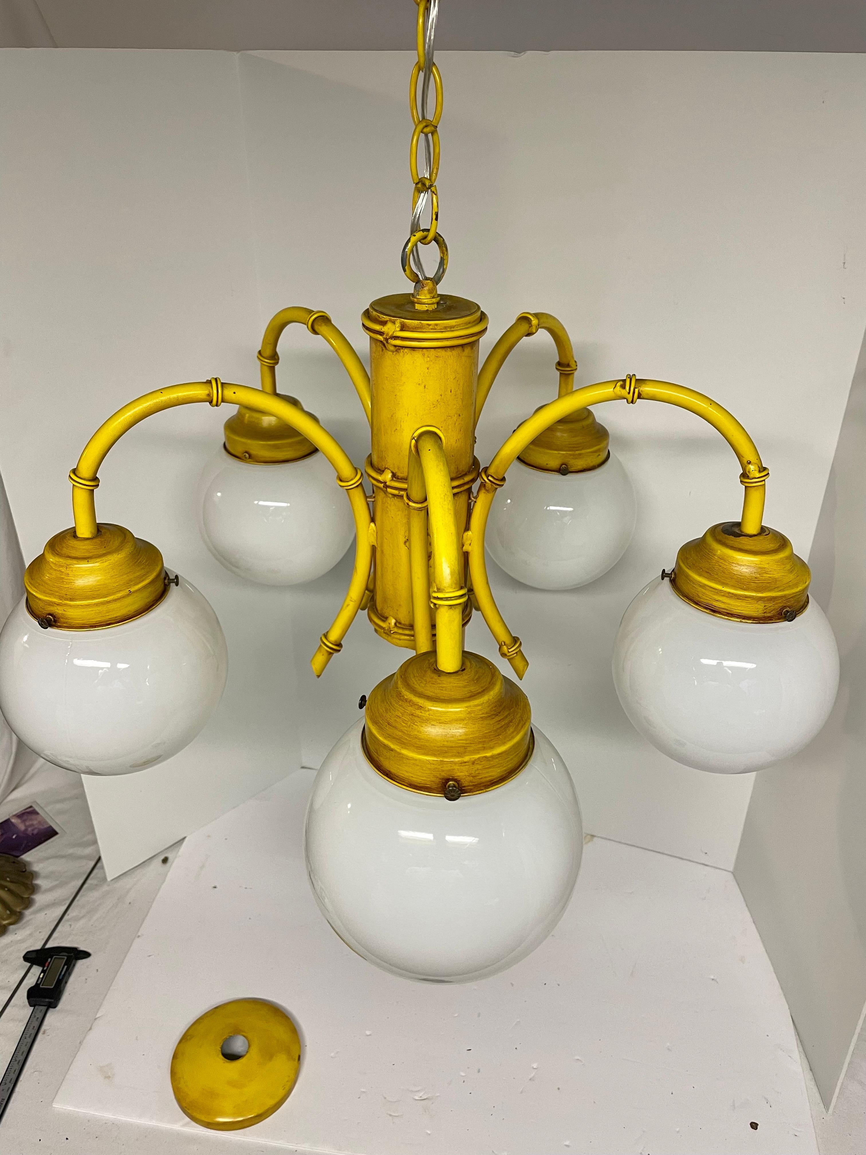 Lampadario Hollywood Regency dipinto in finto bambù proveniente dall'Italia. In vernice gialla originale. Cinque bracci con prese in porcellana e globi originali in vetro bianco da 6 pollici. Alcune scheggiature della vernice dovute all'età e