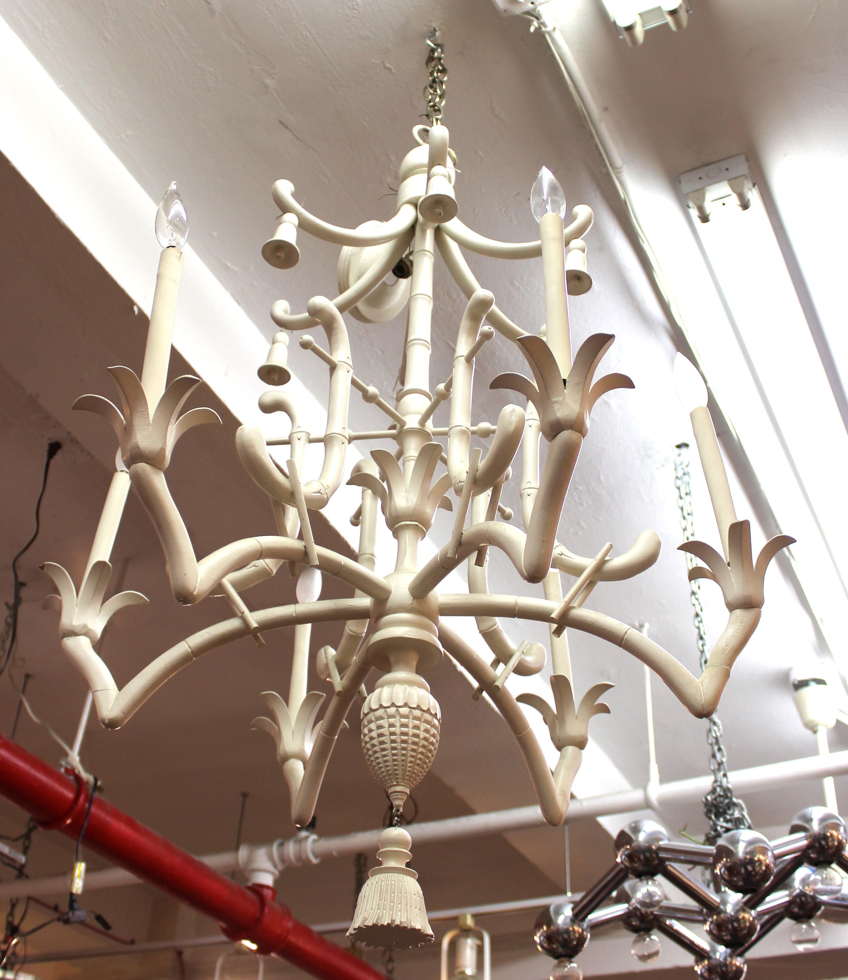 Hollywood Regency Chinese pagoda style faux bamboo chandelier with six arms. The decorative theme features bells and a large tassel. Some age-appropriate wear and old repair work, with one of the leaves of the bulb bases having an edge chipped off.