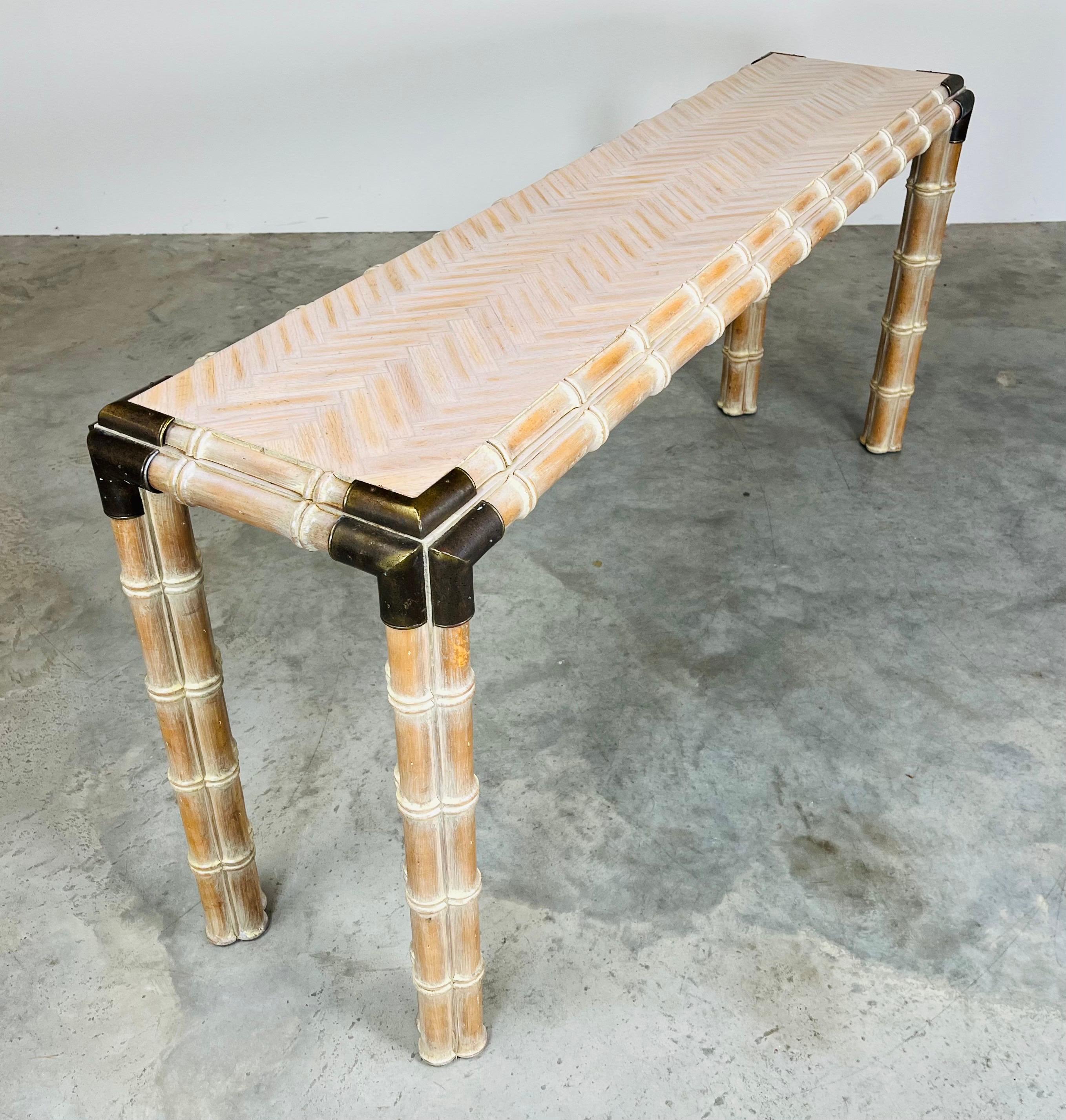 Magnifique table console en faux bambou avec un plateau en marqueterie à motifs croisés, des pieds à triple tige en faux bambou et des supports d'angle en laiton. 
Amérique du Nord vers 1970. 
Dans un état exceptionnel ayant été nettoyé et traité