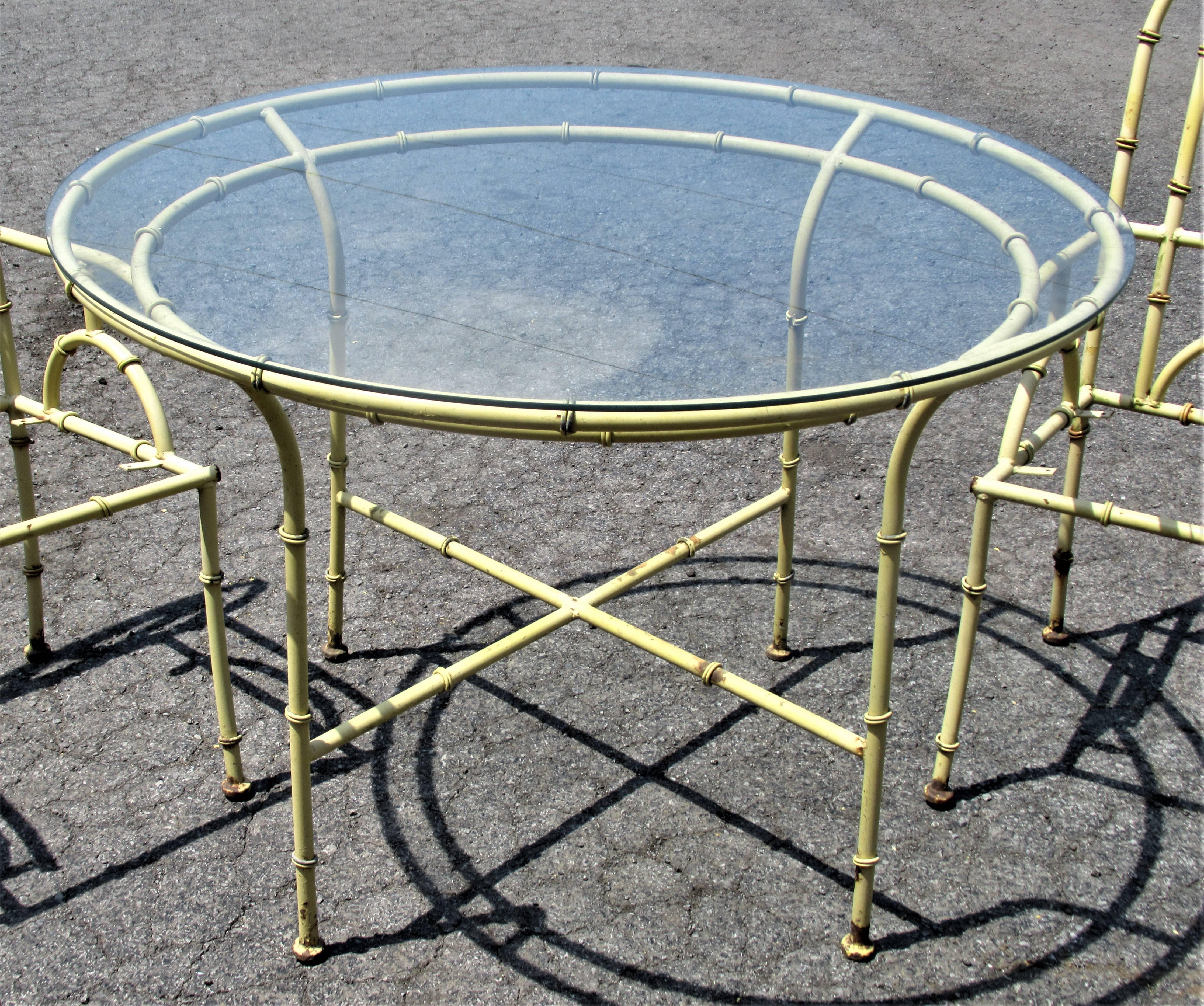Hollywood Regency Chinese Chippendale style metal faux bamboo round glass top dining table with four matching armchairs in original nicely aged very pale chartreuse yellow factory enamel painted surface. Patio garden furniture or interior use.