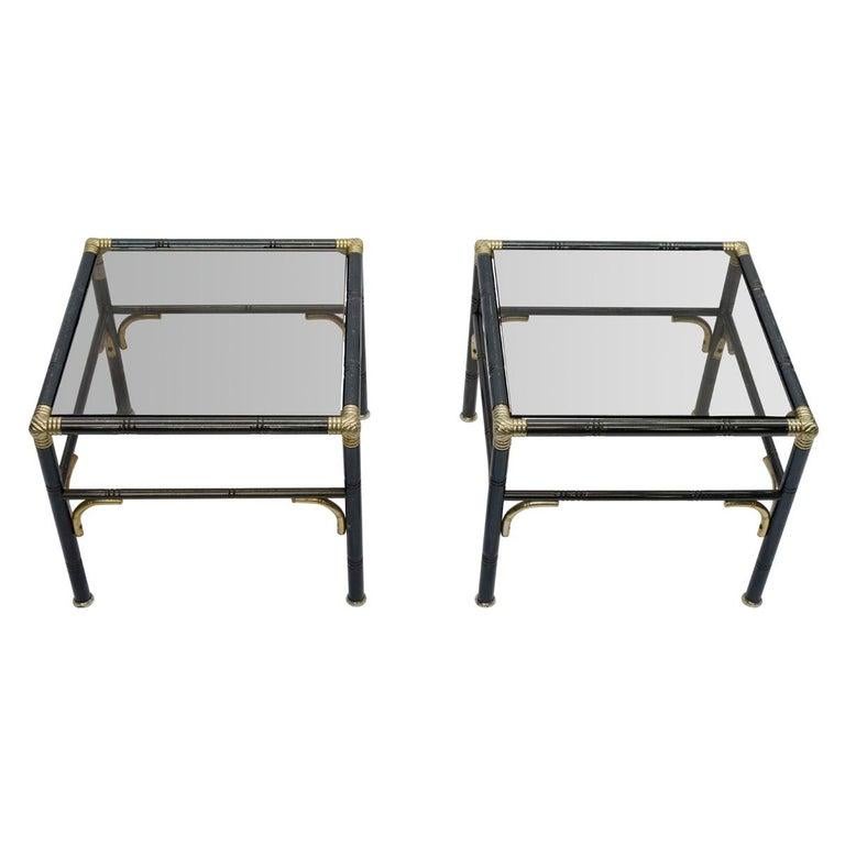 Pair of Hollywood Regency black steel faux bamboo side tables with brass corners and details. The tables are in the manner of Billy Haines. The smoked glass tops finish off the elegance of these beautiful tables.