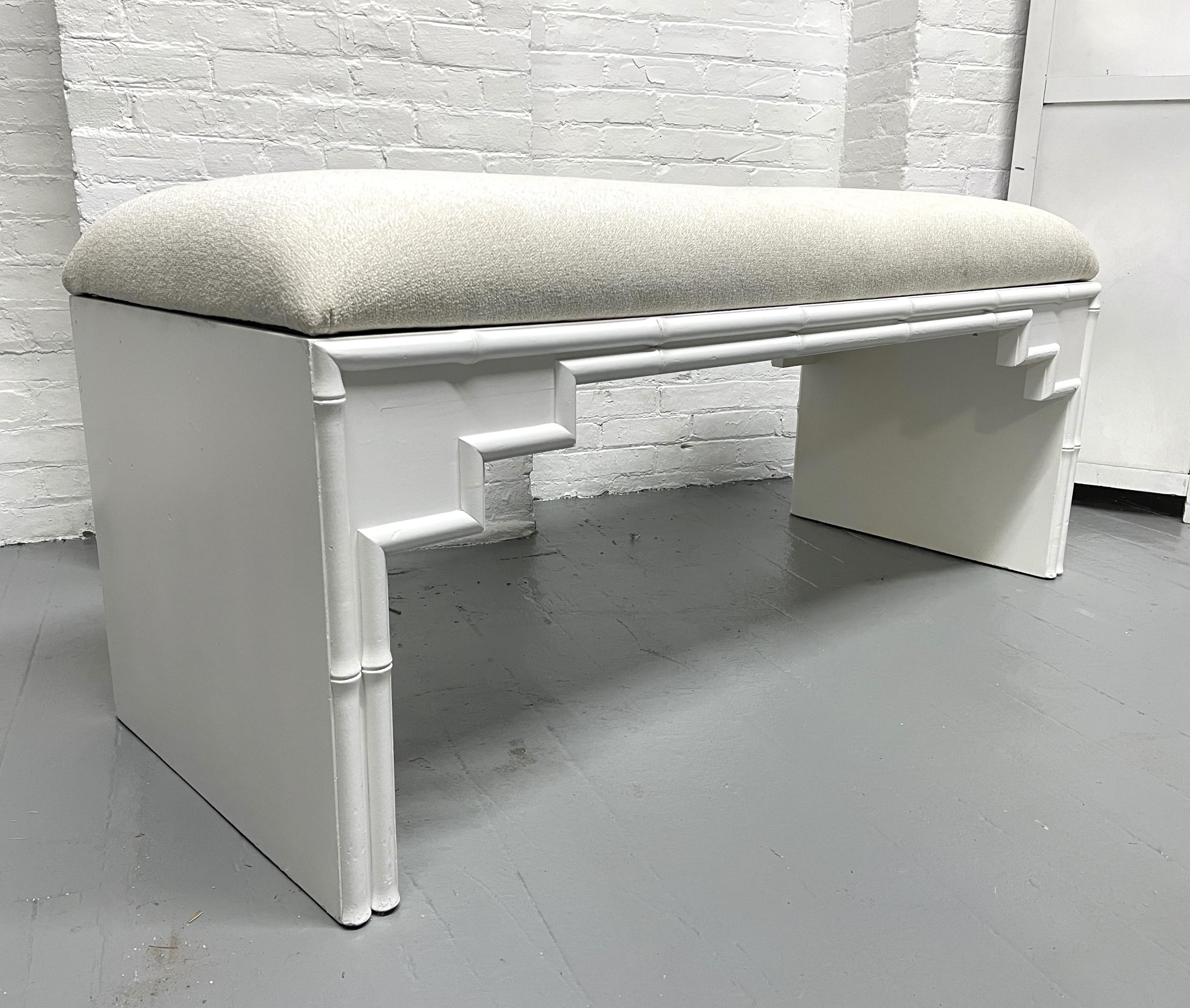 Hollywood Regency faux bamboo upholstered bench. The frame of the bench is wood with a white painted finish and faux bamboo trimming to the front and rear.