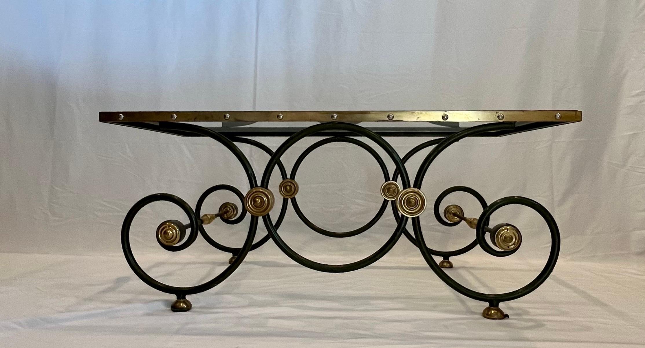 Stunning French Hollywood Regency low table, circa 1950s-1960s. This striking table is designed with a scrolling wrought iron base, a glass top sits in brass gallery with chrome stud caps. Green painted patina. Brass lettuce cup medallions.
Curbside