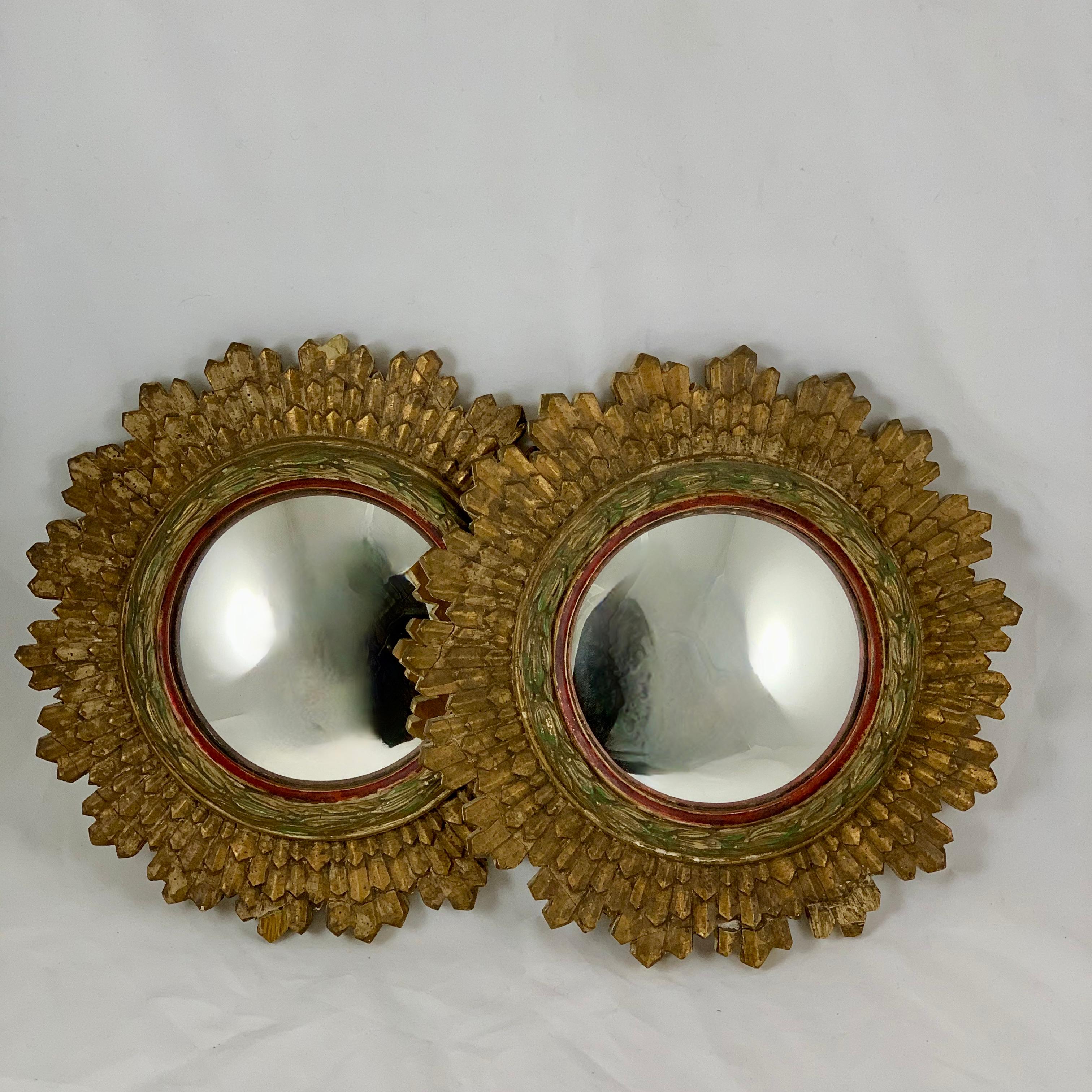 A pair of Hollywood Regency Period giltwood sunburst wall mirrors, from France, circa 1920s.

Made of painted and gilded gesso on wood, round in shape, the convex mirrors are set in a running laurel leaf border ring painted in a soft green gold,