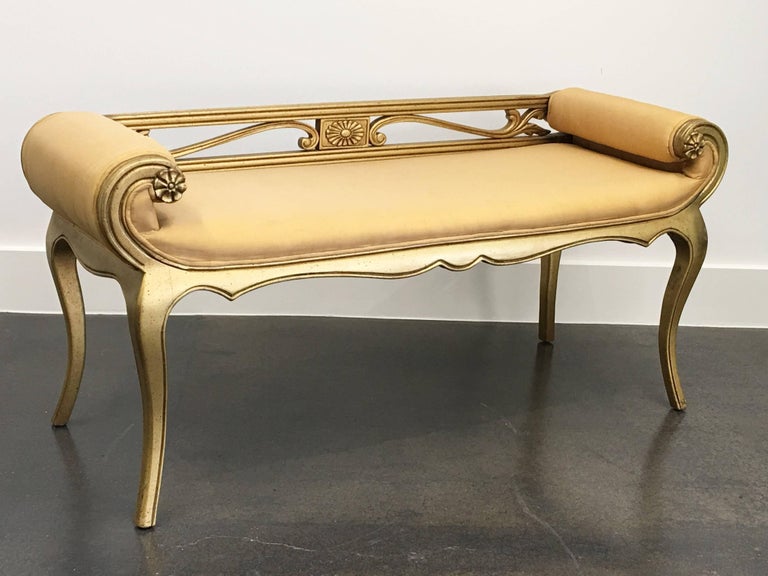 Vintage Hollywood Regency French Louis XV style carved bench. It features a beautifully carved solid wood acanthus leaf designed frame with scrolled arms and shapely cabriole legs with silk upholstery.