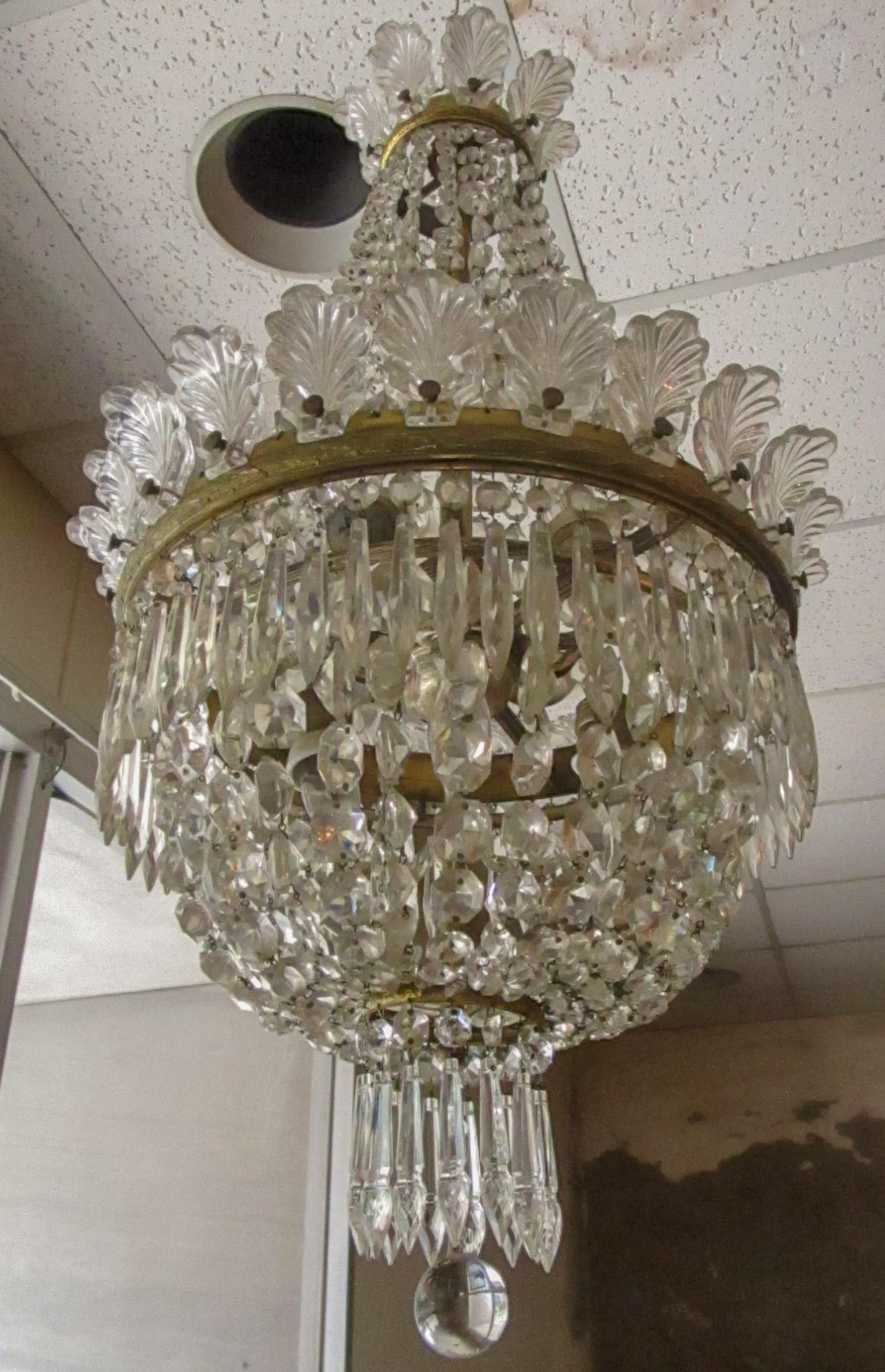 This gorgeous Hollywood Regency chandelier might have been used by renowned designers Dorothy Draper and Billy Haines. Featuring an elegant elongated shape, highlights include sparkling teardrop prisms, beaded festoons, double crowns of shell shaped