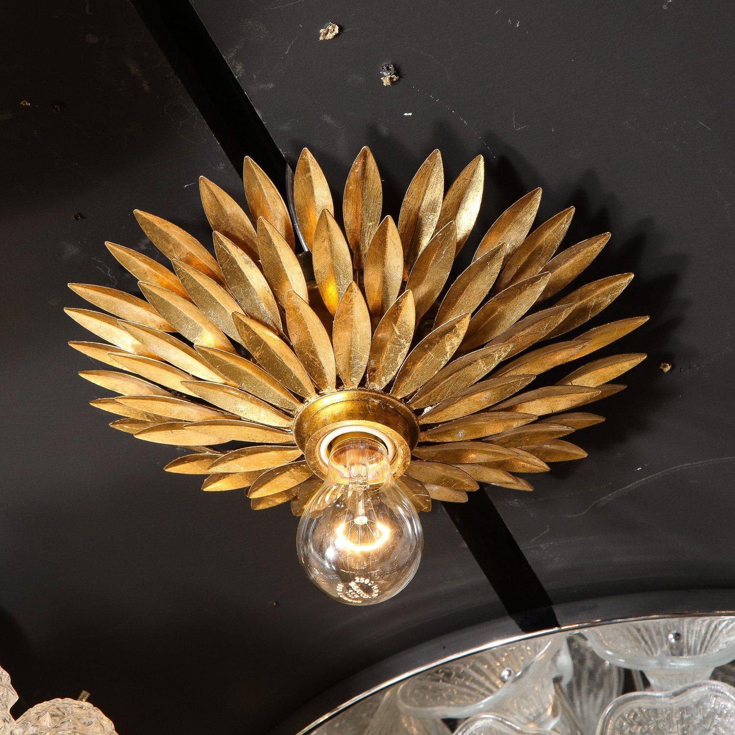 Pair of Hollywood Regency gilded brass starburst flush mount chandeliers. Individual leaves with only midrib fold detailing are arranged across three separate, tiered layers. A brass dipped bulb diffuses light to the sides. This set has been